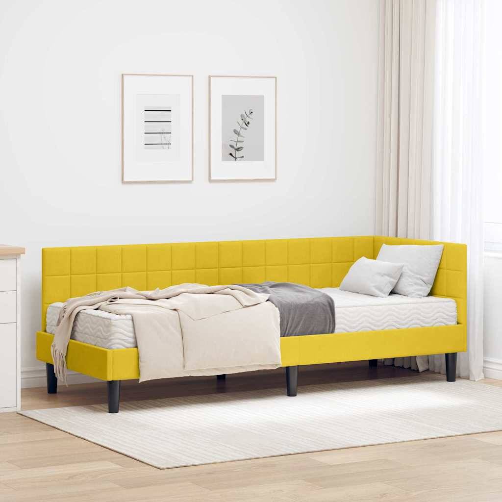 Ein modernes Schlafzimmer mit einem gelben Schlafsofa, grauen und beigen Decken und zwei gerahmten Kunstwerken an der Wand. Natürliches Licht fällt durch ein Fenster.