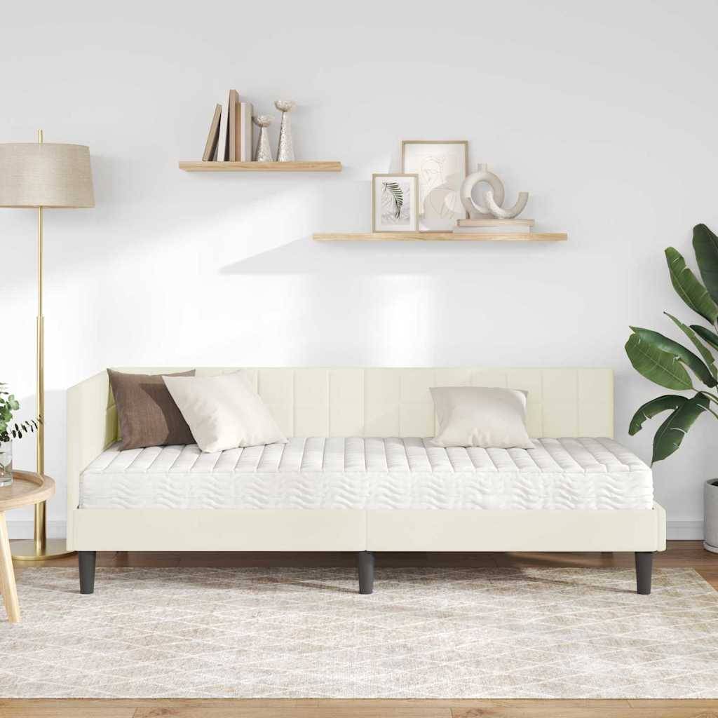 Ein minimalistisches Wohnzimmer zeigt ein weißes Tagesbett mit Kissen, eine hohe Stehlampe und an der Wand montierte Regale, die Bücher und Kunst tragen, vor einem hellfarbenen Wandhintergrund.