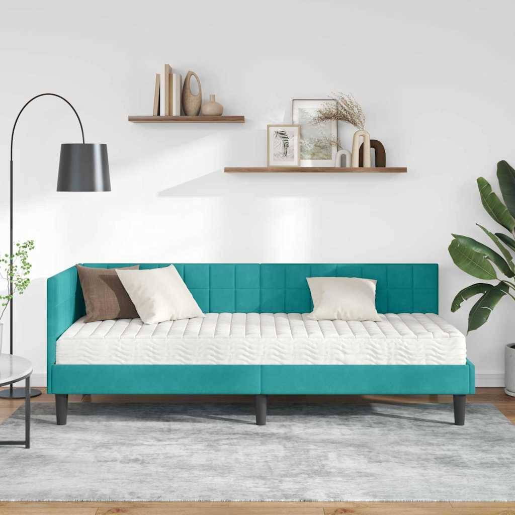 Ein modernes Wohnzimmer mit einem türkisfarbenen Schlafsofa, weißen Kissen, einer schwarzen Stehlampe und Wandregalen mit Deko vor einer hellblauen Wand.