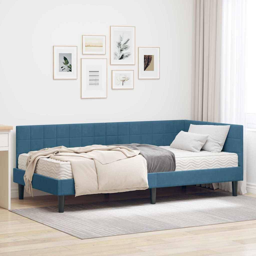 Ein modernes Schlafzimmer zeigt ein blaues Tagesbett mit beiger Bettwäsche, einen weißen Schreibtisch und mehrere gerahmte Kunstwerke an der Wand. Natürliches Licht durchflutet den Raum.