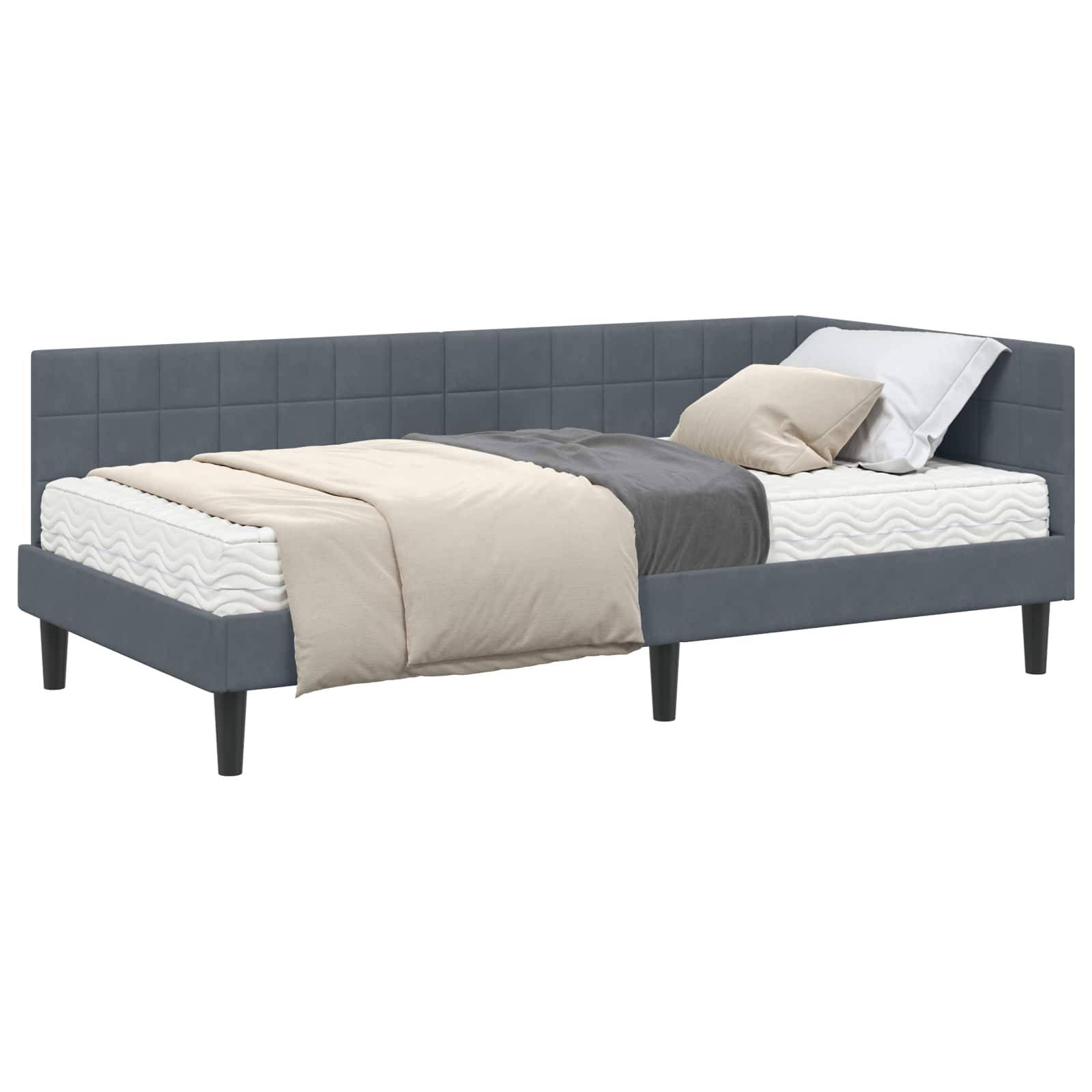 Eine graue gepolsterte Tagesbett mit einer beigen Decke und zwei Kissen, vor einem weißen Hintergrund.