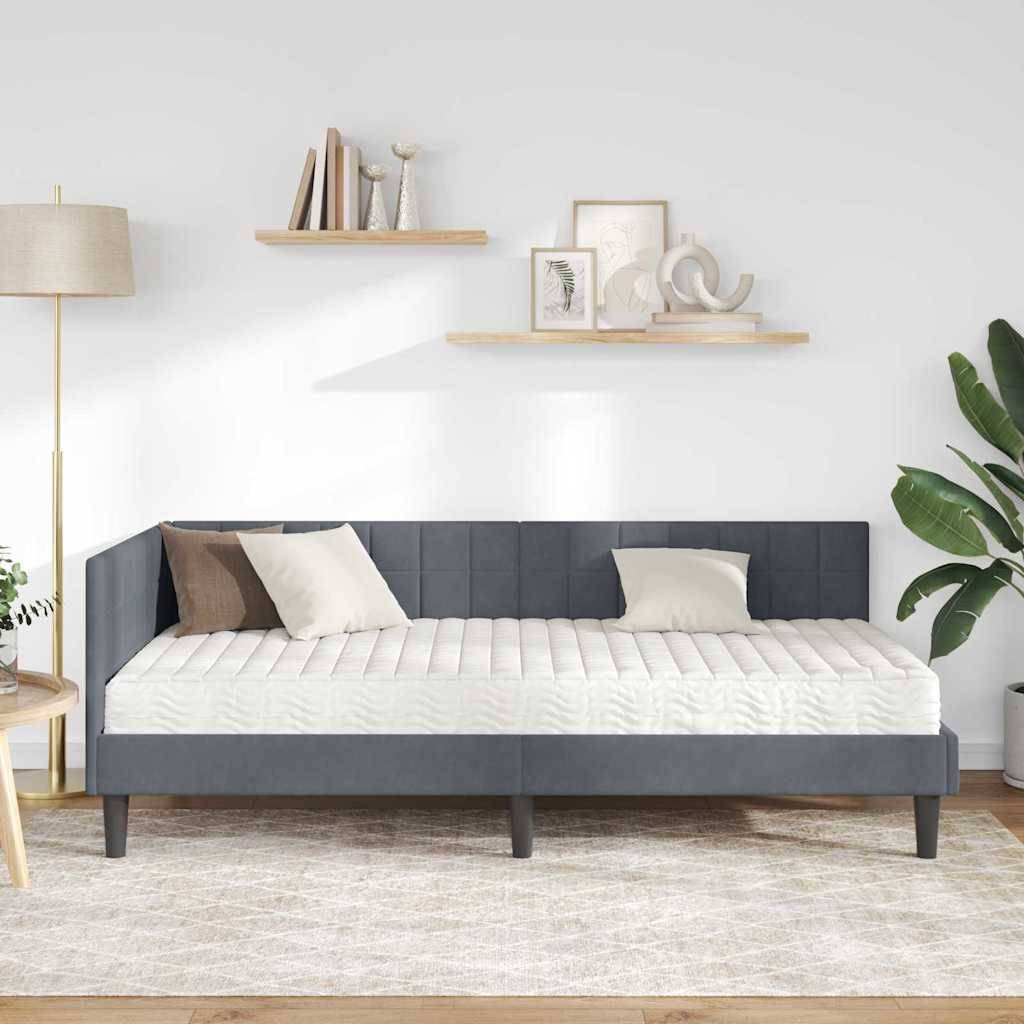 Ein modernes Schlafzimmer zeigt ein graues gepolstertes Bett mit weißen und braunen Kissen, eine Stehlampe, schwebende Regale mit minimaler Dekoration und eine große grüne Pflanze.
