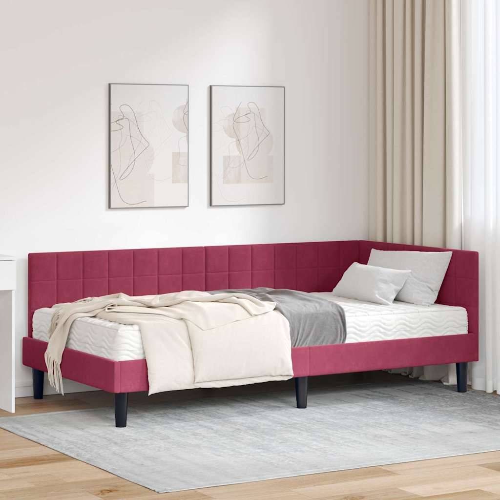 Ein Raum mit einem roten Eckschlafsofa, grauem Teppich, weißen Wänden und zwei abstrakten Gemälden. Helle Vorhänge fallen neben dem Sofa herab.