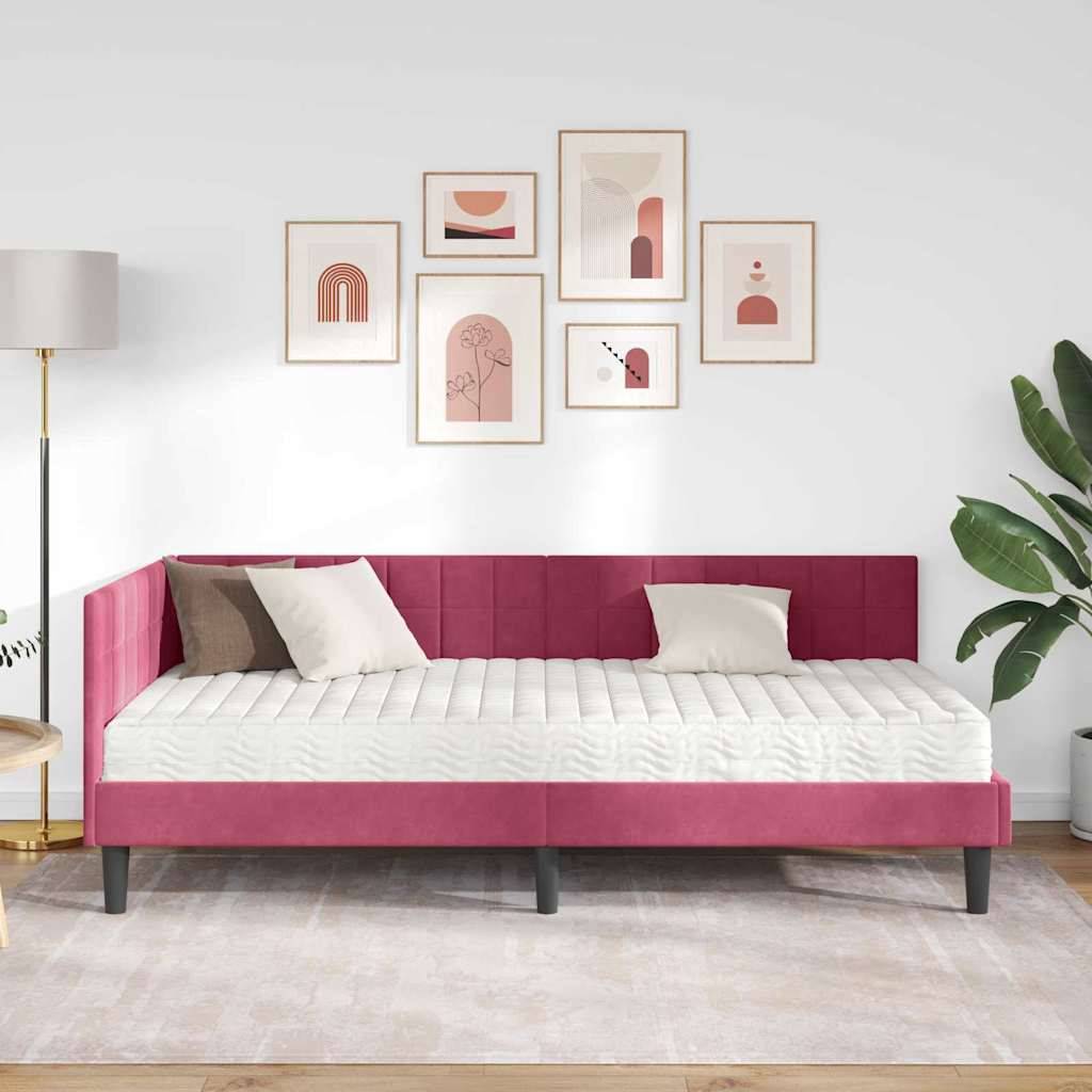 Ein modernes Schlafzimmer mit einem rot gepolsterten Bett, weißer Bettwäsche, einer Lampe und Wandkunst. Eine Topfpflanze bringt Grün in die minimalistische Einrichtung.