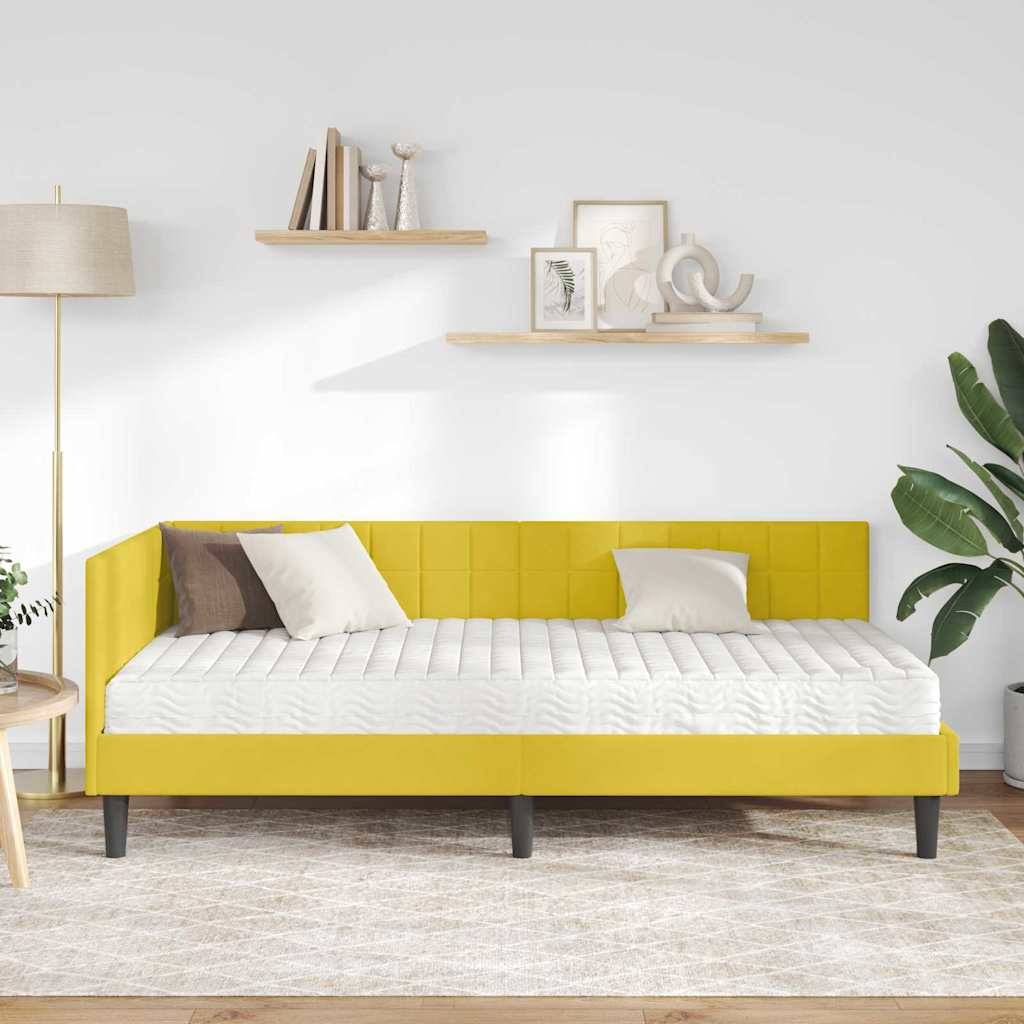 Ein moderner Raum mit einem minimalistischen gelben Schlafsofa, zwei Kissen, einem Holzbeistelltisch, einer Stehlampe, Wandregalen mit Deko und einer Pflanze.
