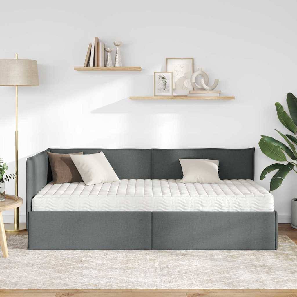 Ein moderner Wohnraum mit einem grauen Tagesbett, ausgestattet mit weißen und braunen Kissen, flankiert von einer Stehlampe, Holzregalen und einer großen Zimmerpflanze.