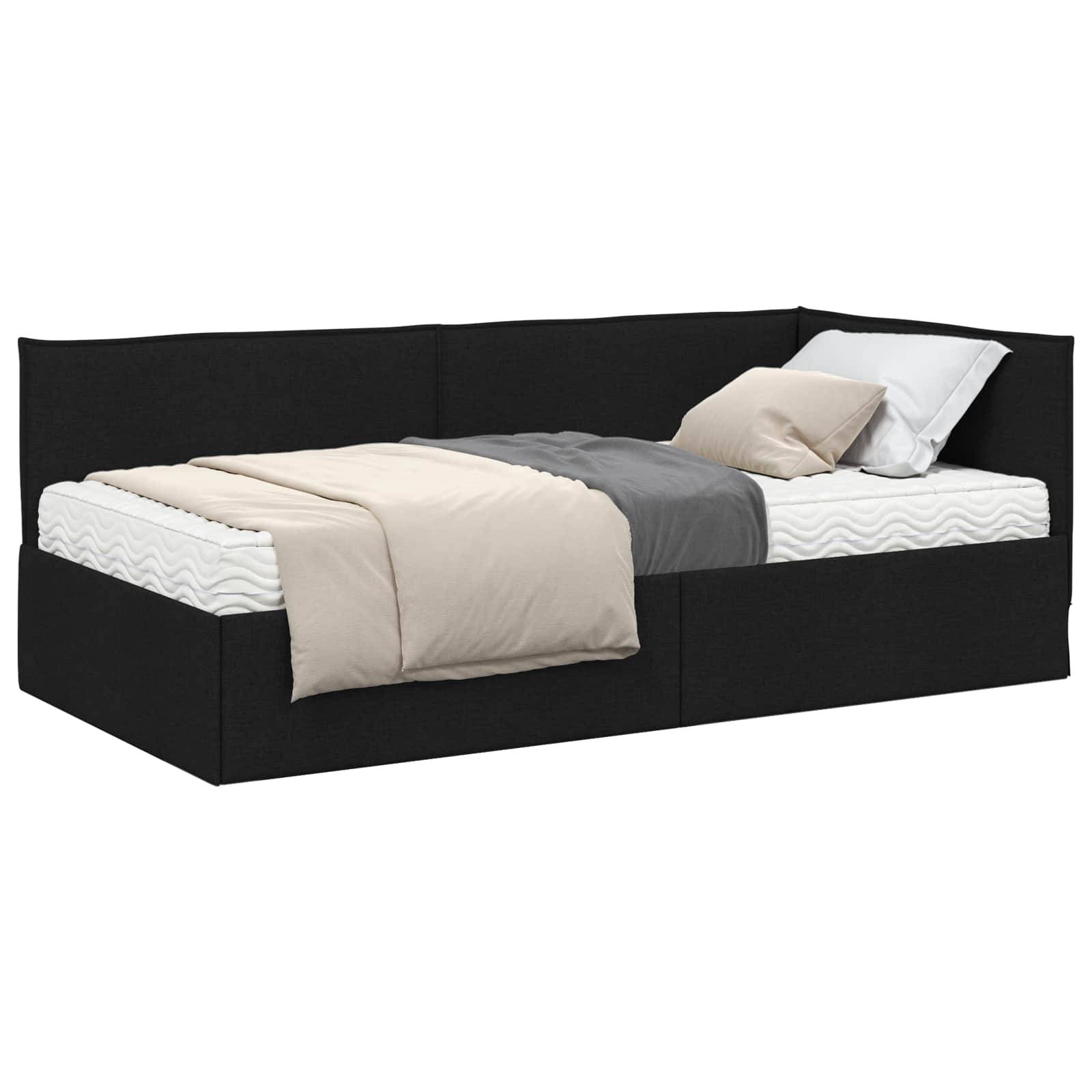 Ein schwarzes Tagesbett mit einer Matratze ist mit einer grauen Decke und beige Bettwäsche dekoriert. Ein weißes Kissen ist am Kopfende des Bettes platziert.