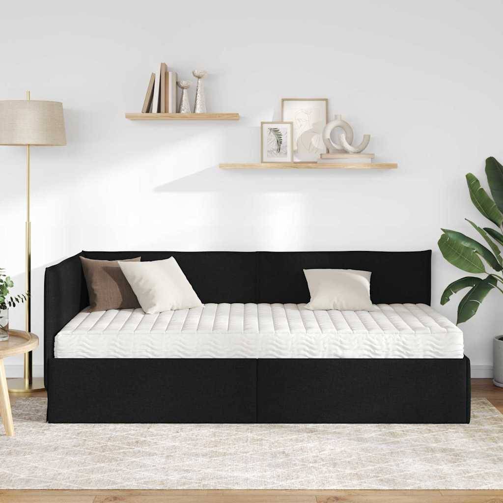 Ein moderner Wohnraum zeigt ein schwarzes Tagesbett mit weißen Kissen, Zierkissen, einer Stehlampe, Pflanzen und minimalistischen Wandregalen.