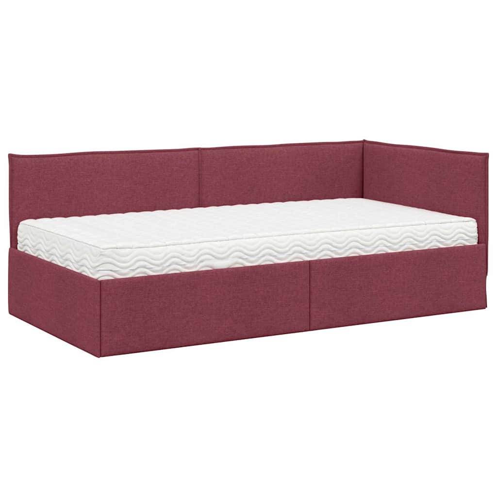 Ein roter gepolsterter Tagesbett mit einer weißen Matratze darauf. Das Bett hat eine Rückenlehne und eine Armlehne an einer Seite, was eine L-Form ergibt.