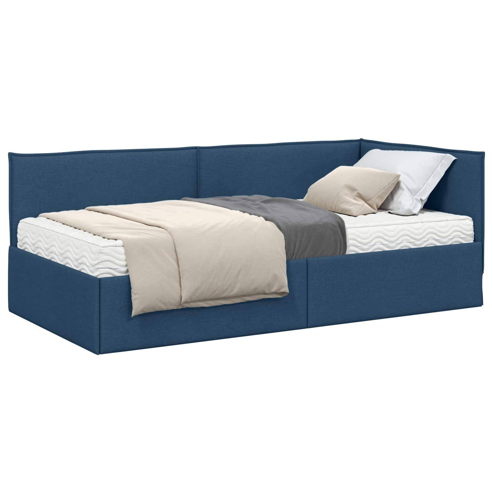 Ein blau gepolstertes Tagesbett mit einer beige-grauen Decke und Kissen auf einer wellengemusterten Matratze.