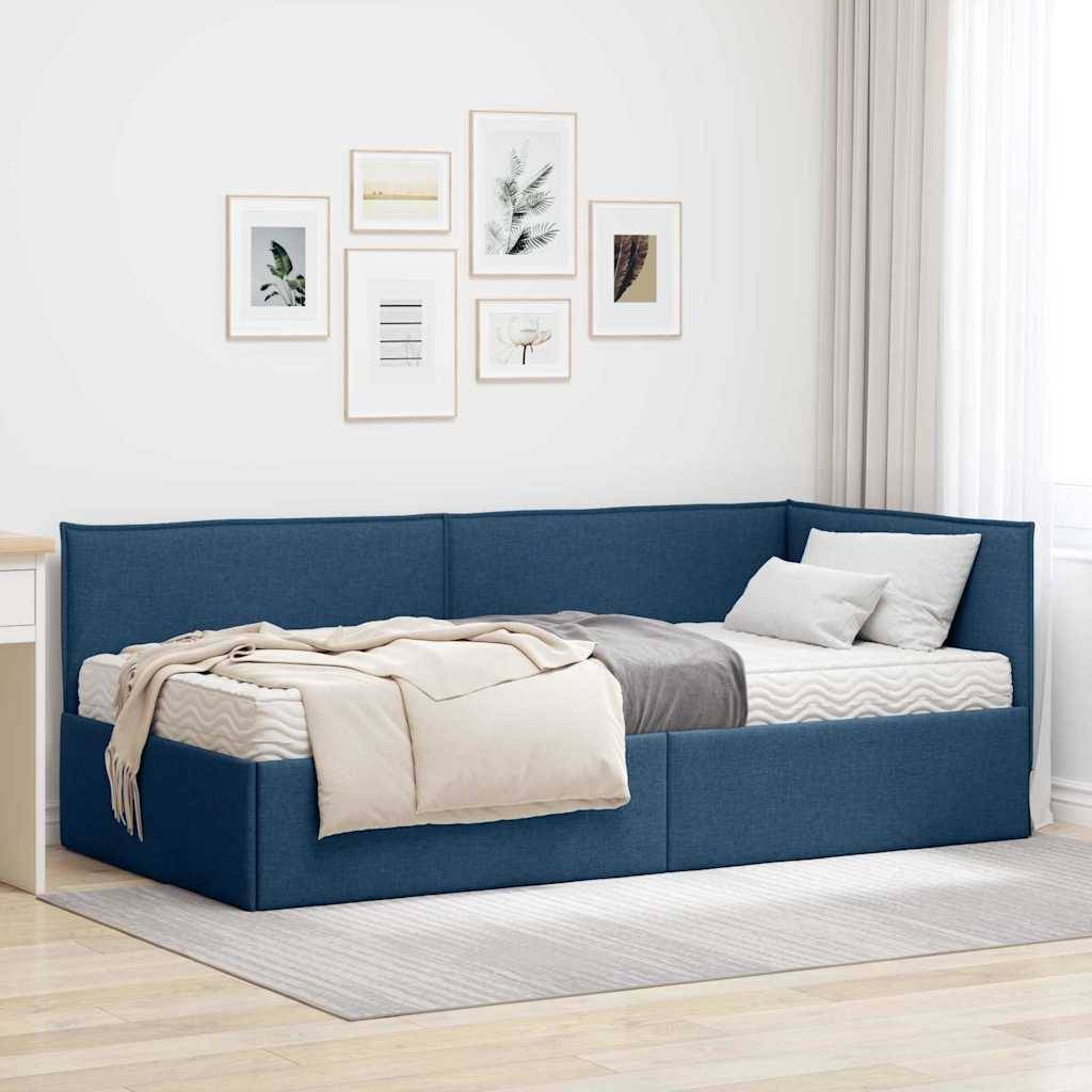 Ein gemütliches blaues Tagesbett mit einer beigen Decke und Kissen, platziert in einem hell beleuchteten Raum mit gerahmten Kunstwerken an der Wand und einem weißen Schreibtisch in der Nähe.