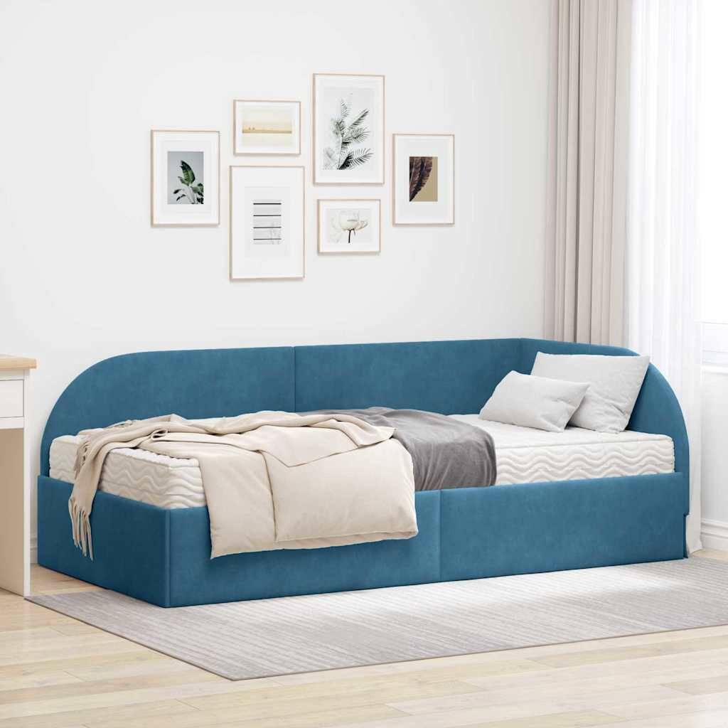 Ein stilvolles blaues Tagesbett mit weißen und grauen Kissen steht in einem modernen Schlafzimmer mit gerahmten Kunstwerken an der Wand und einem grauen Teppich auf dem Boden.