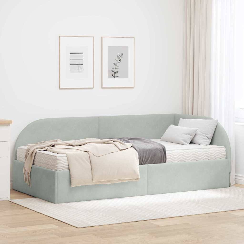 Ein minimalistisches Schlafzimmer zeigt ein hellgrünes, umlaufendes Bett mit beigen und grauen Kissen und einer Decke, darüber gerahmte Kunstwerke, alles in weichem, natürlichem Licht.