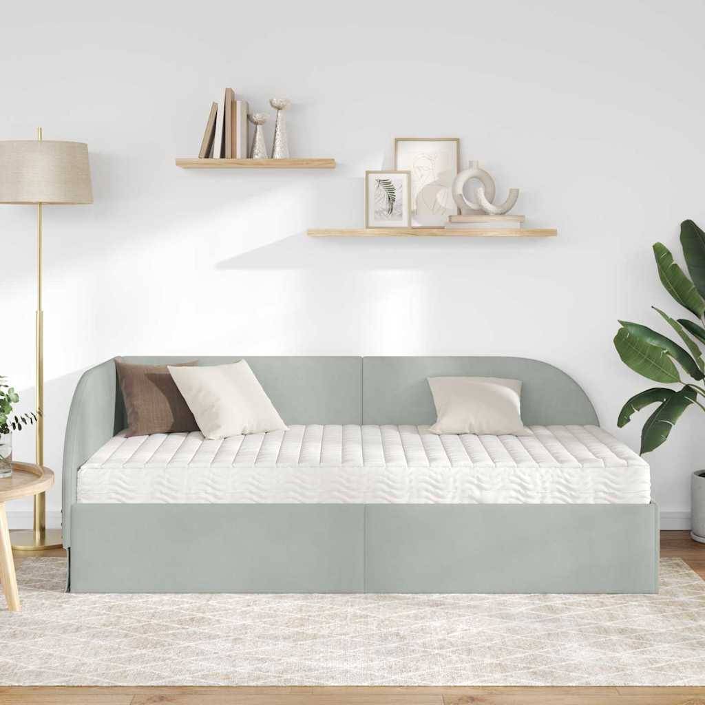 Ein modernes Wohnzimmer zeigt ein hellgraues Sofa mit zwei weißen Kissen, eine Stehlampe, Wandregale mit Dekorationen und einen Teppich auf hellem Holzboden.
