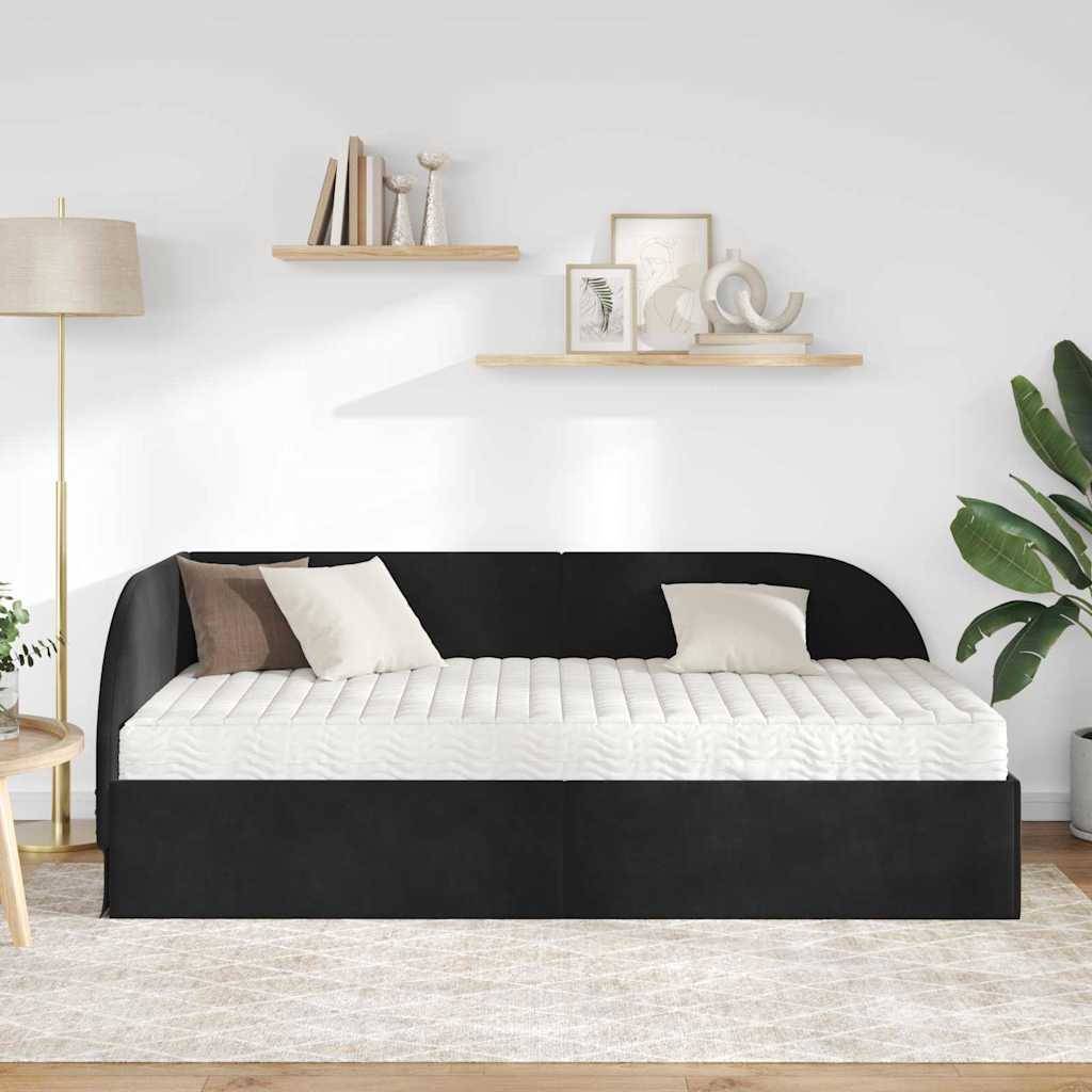 Ein moderner Wohnraum mit einem schwarzen Tagesbett, das mit weißen und braunen Kissen ausgestattet ist, einer Stehlampe, Regalen mit Dekorationen und einer großen Pflanze.
