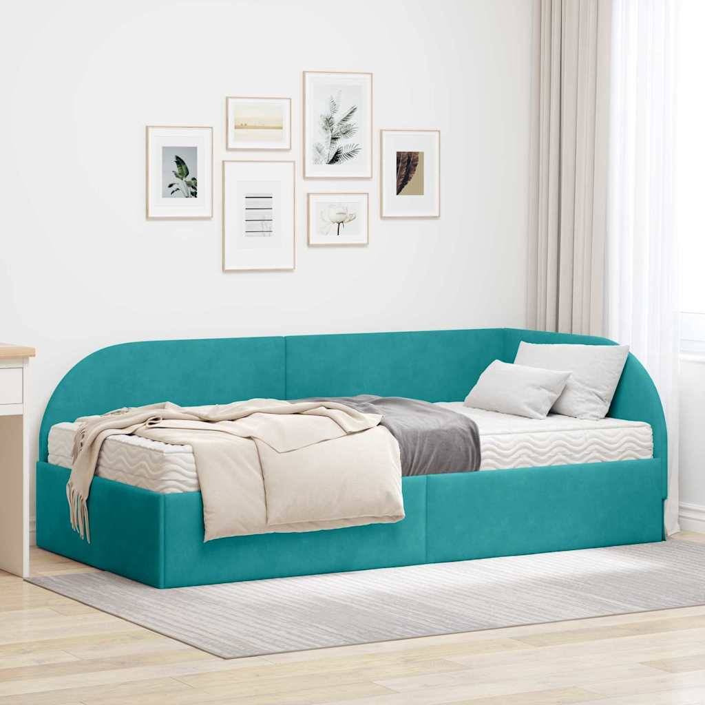Ein türkisfarbenes gepolstertes Tagesbett mit einer beigen Decke und Kissen an einer Wand mit gerahmter Kunst. Rechts befindet sich ein bodenlanger Vorhang.