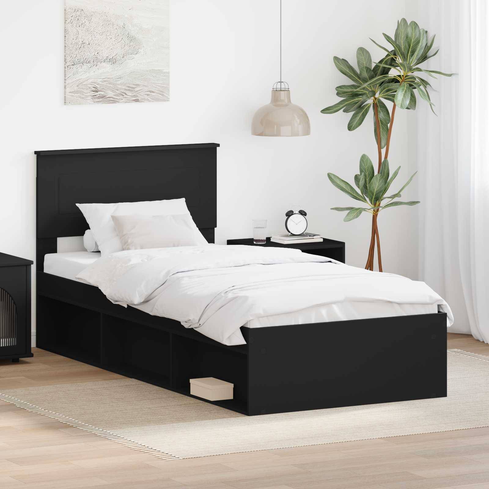 Ein modernes Schlafzimmer mit einem schwarzen Bett mit Schubladen zur Aufbewahrung, weißer Bettwäsche, einem Nachttisch, einer hängenden Lampe und einer Topfpflanze in einer Ecke.