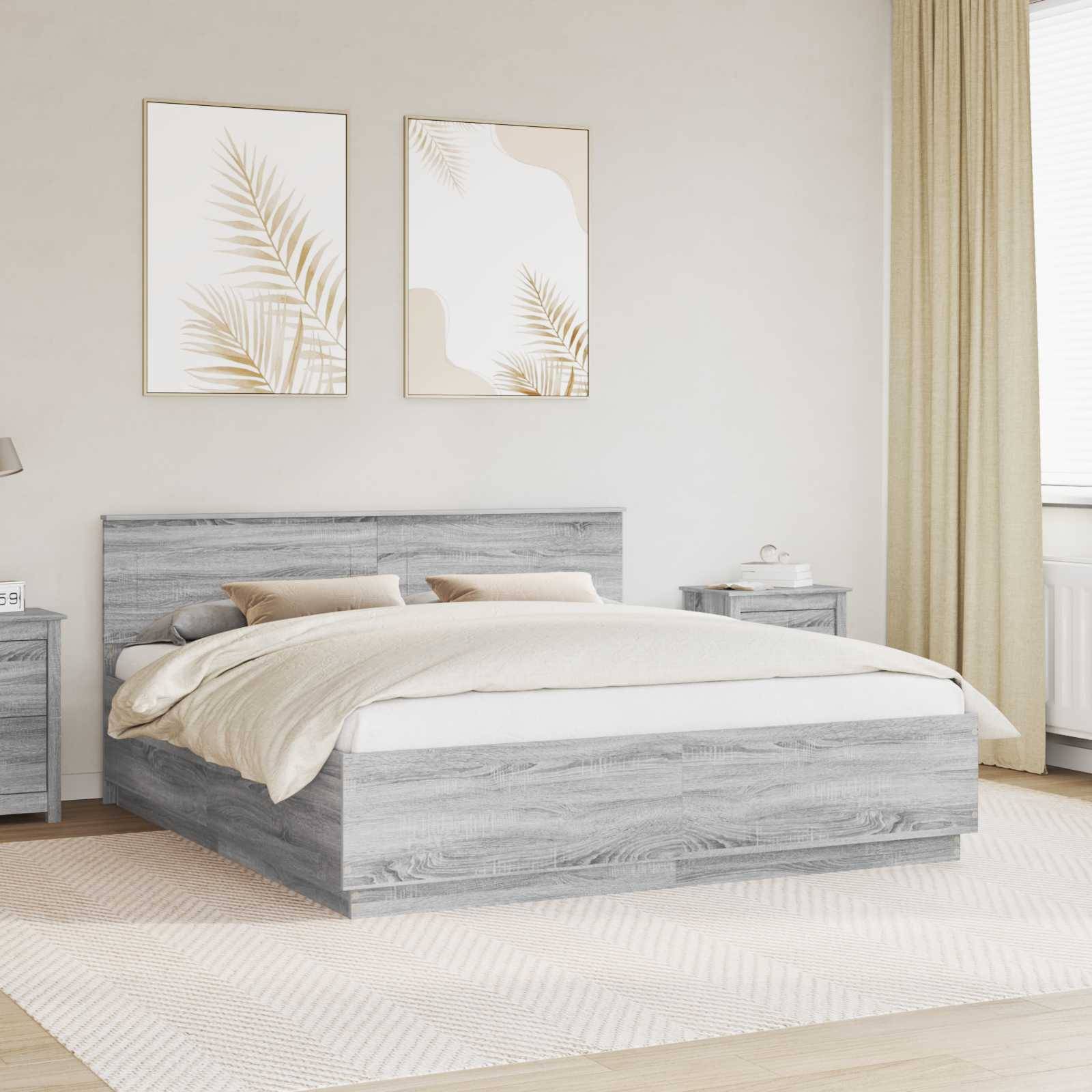 Ein modernes Schlafzimmer mit einem grauen Holzbett, beigefarbener Bettwäsche, zwei gerahmten botanischen Drucken an der Wand und einem hellbeigen Vorhang.