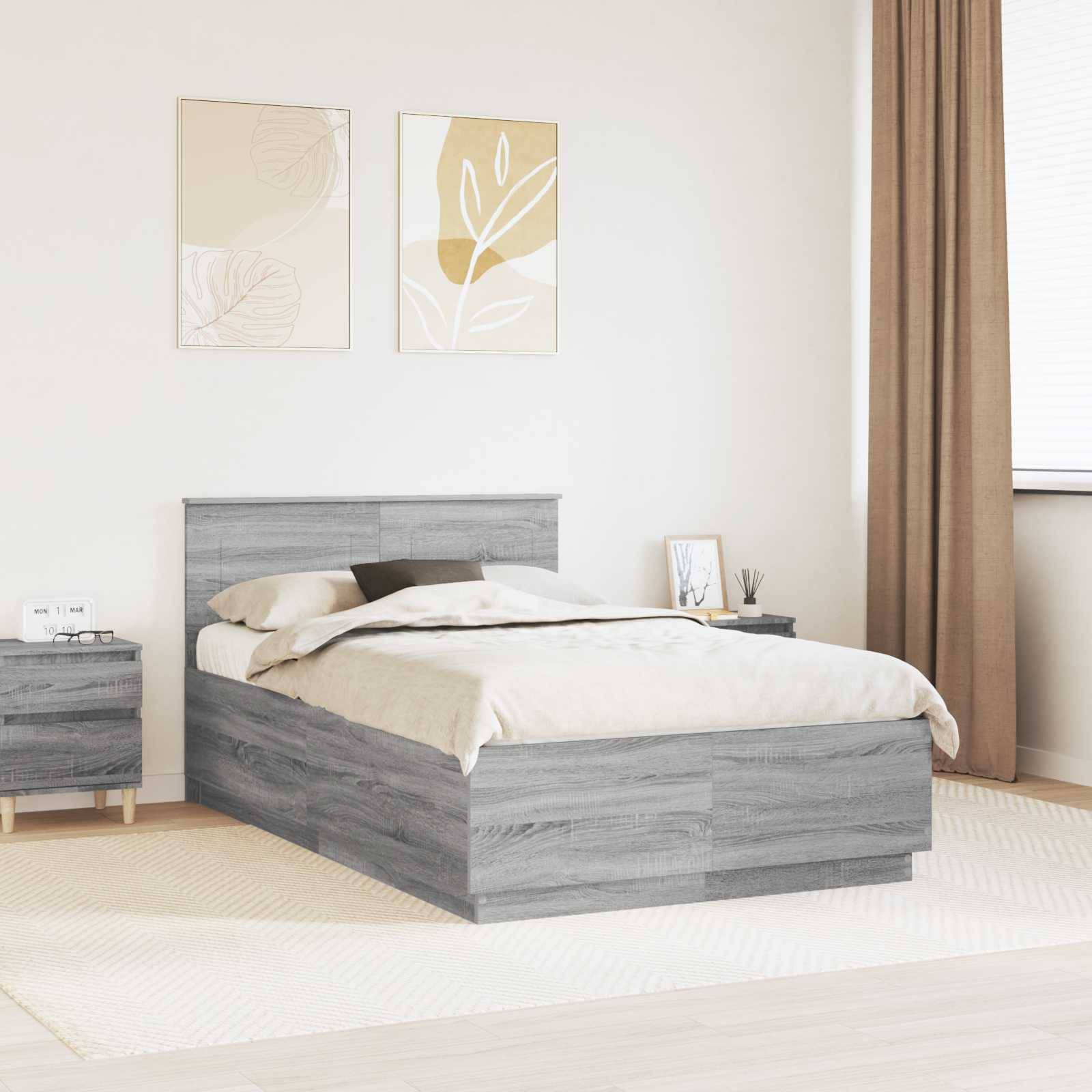 Ein modernes Schlafzimmer mit einem grauen Holzbett, beigen Bettwäsche und einem passenden Nachttisch. Zwei gerahmte Blattkunstwerke hängen über dem Bett.