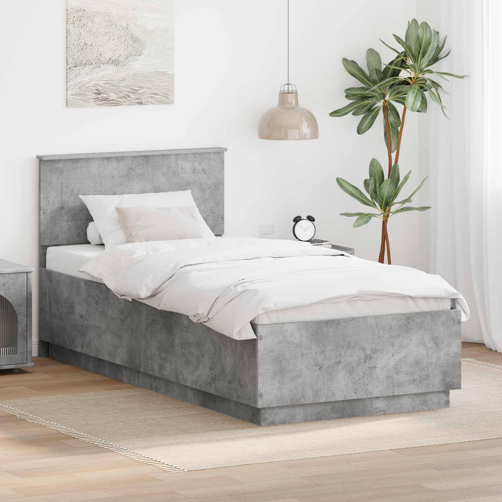 Ein modernes Schlafzimmer zeigt ein graues Bett mit weißer Bettwäsche, einen runden Nachttisch, eine Topfpflanze und eine Pendelleuchte, die eine gemütliche Atmosphäre schafft.