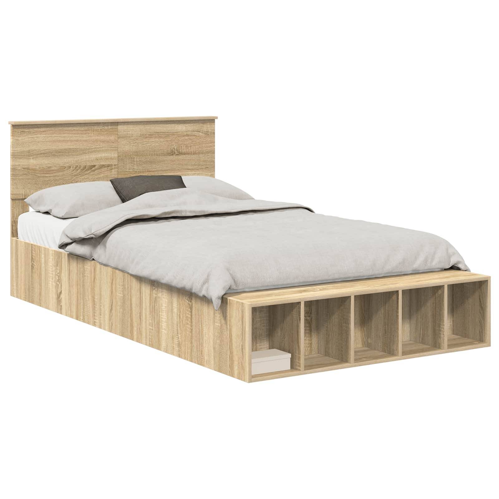 Ein Holzbett mit Kopfteil und eingebauten Stauraum am Fußende; ausgestattet mit grauer Bettwäsche und einem Kissen obenauf.