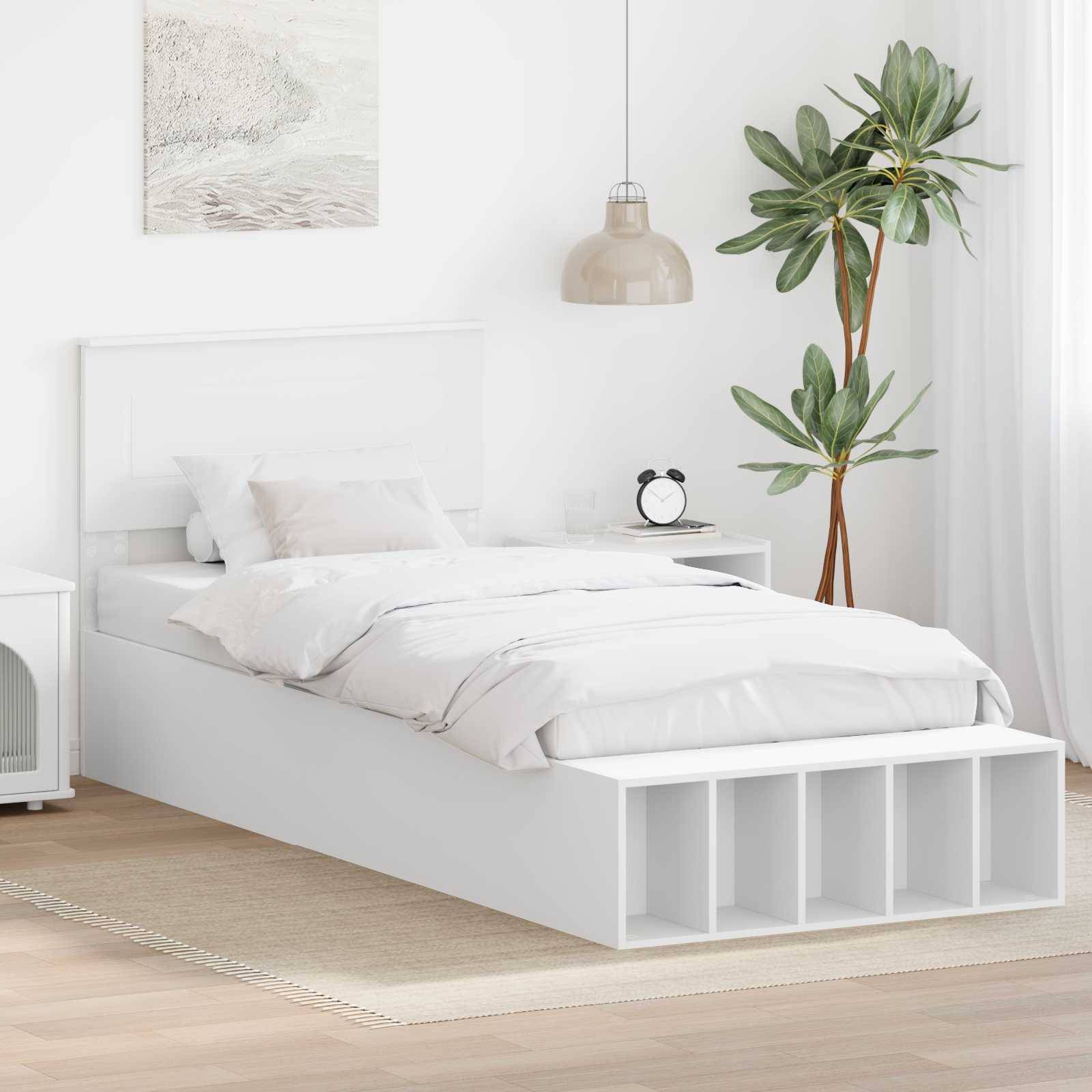 Ein modernes Schlafzimmer mit einem weißen Bett, einem Nachttisch mit einer Lampe und einer hohen Topfpflanze. Ein gerahmtes Wandkunstwerk hängt über dem Bett.