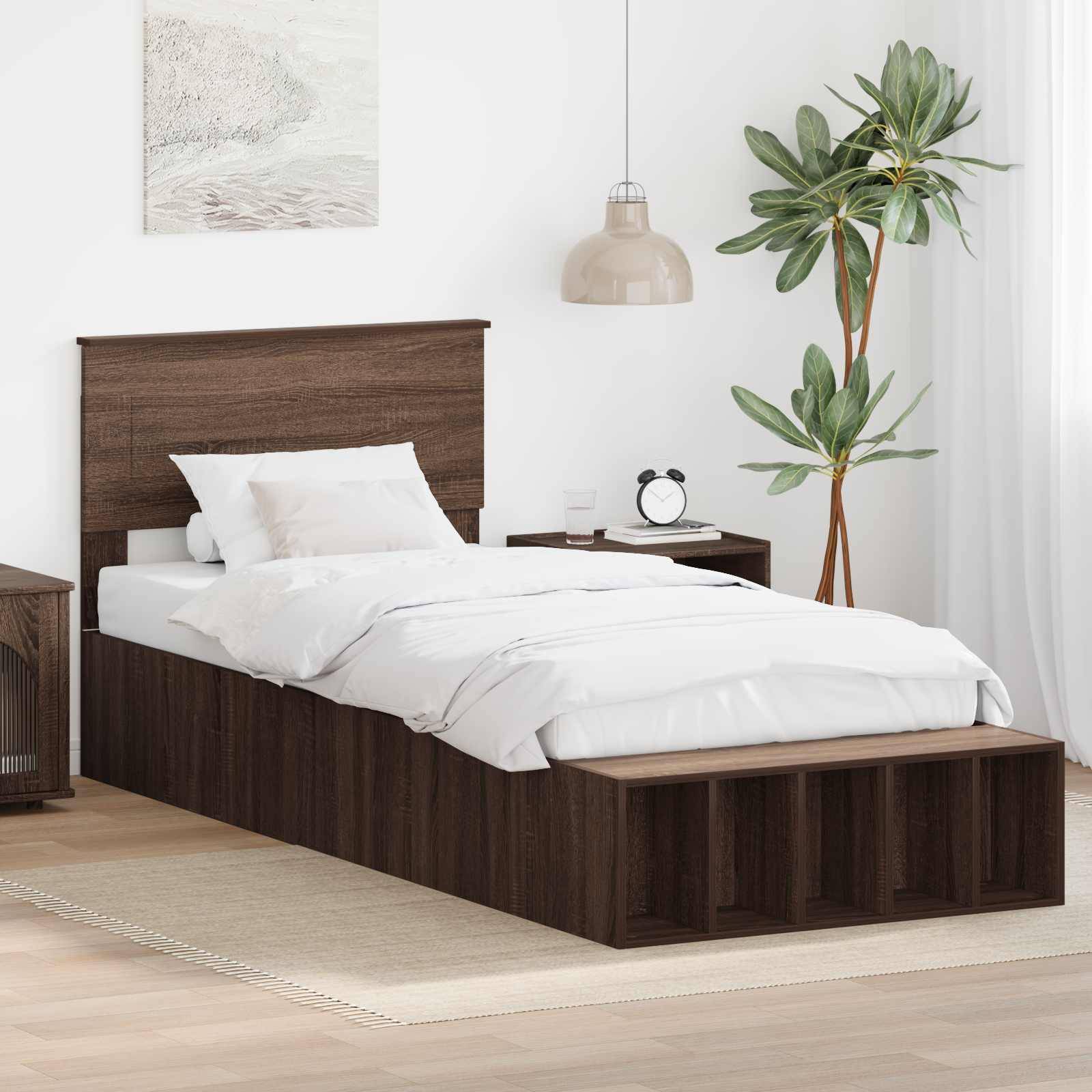 Ein modernes Schlafzimmer zeigt ein Bett aus dunklem Holz mit weißer Bettwäsche, einen Nachttisch mit einer Lampe und einer Uhr sowie eine Topfpflanze in der Ecke.