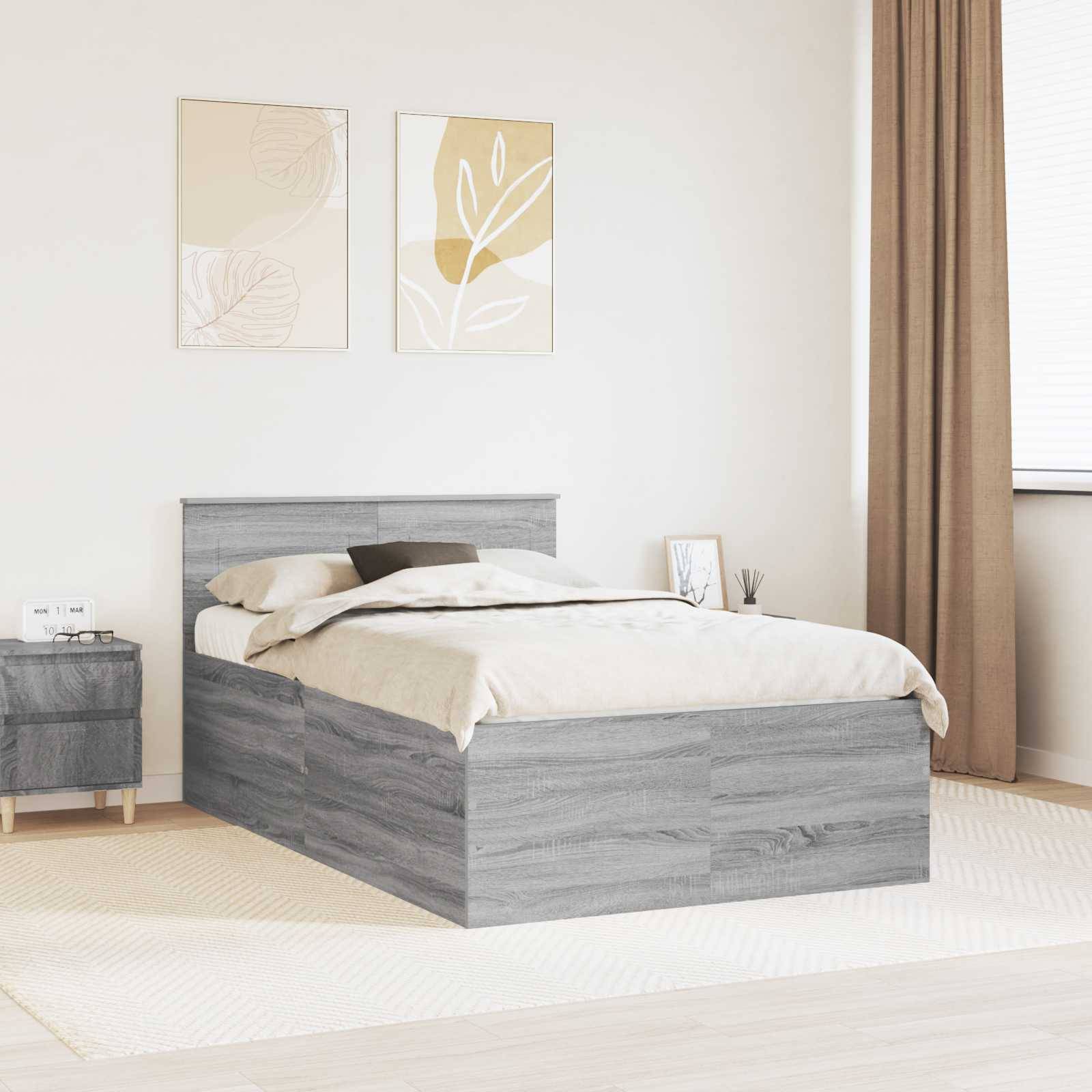 Ein modernes Schlafzimmer zeigt ein graues Holzbett mit beigen Bettwäschestücken, einen passenden Nachttisch, abstrakte Kunstwerke darüber und ein bodentiefes Fenster.