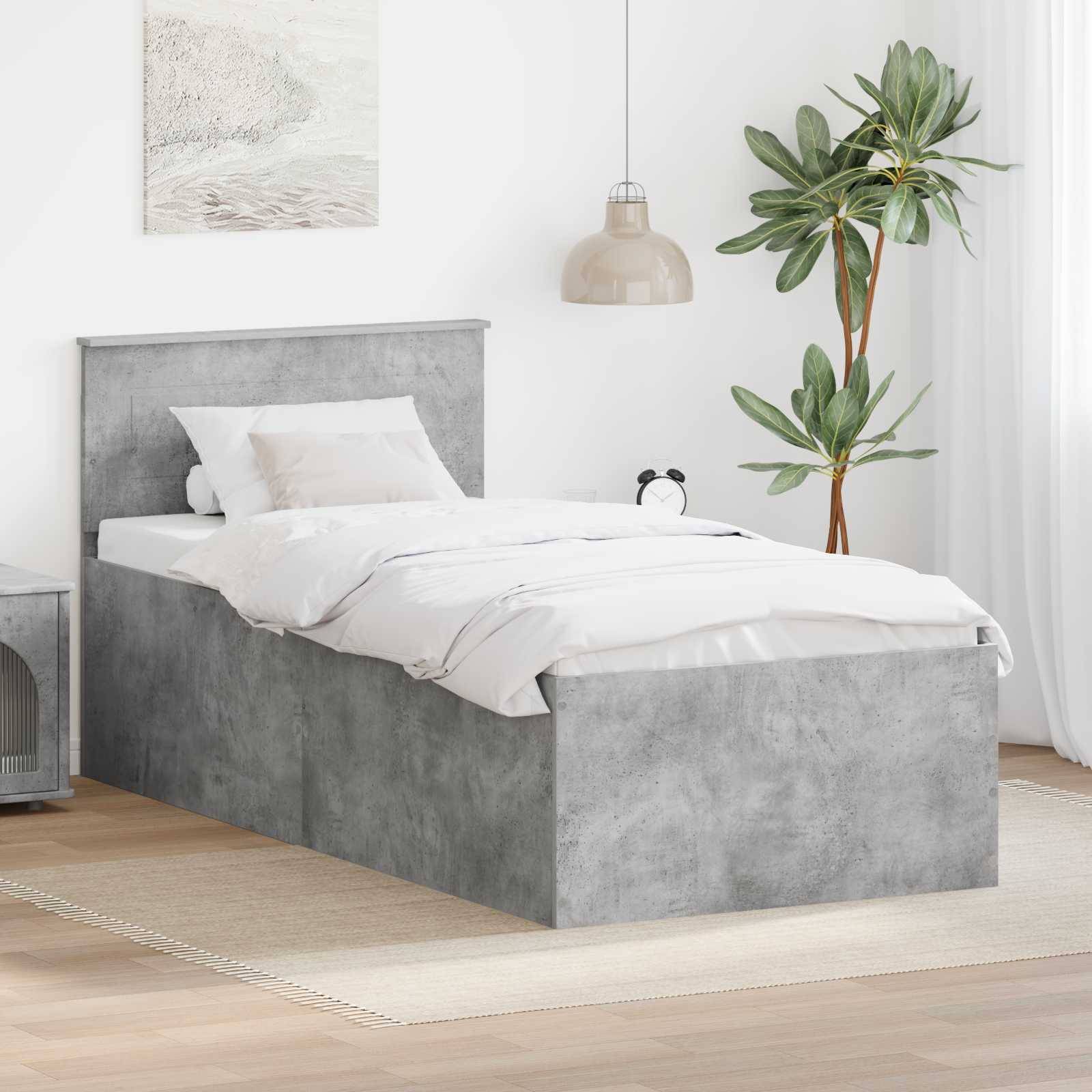 Graues texturiertes Bett mit weißer Bettwäsche in einem minimalistischen Schlafzimmer mit Nachttisch, Pendelleuchte und Topfpflanze.