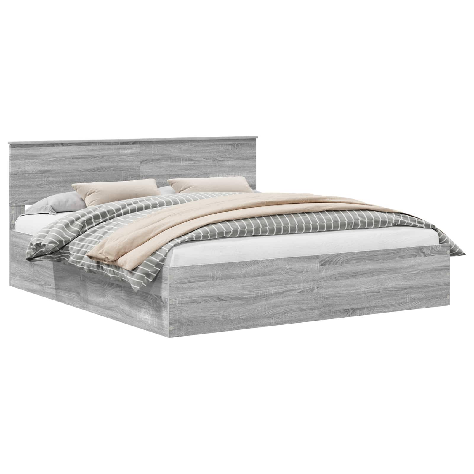 Ein grauer Holzbett mit einem Kopfteil, ordentlich bezogen mit einer weißen Matratze, beigen Kissen und einer grauen gestreiften Decke.
