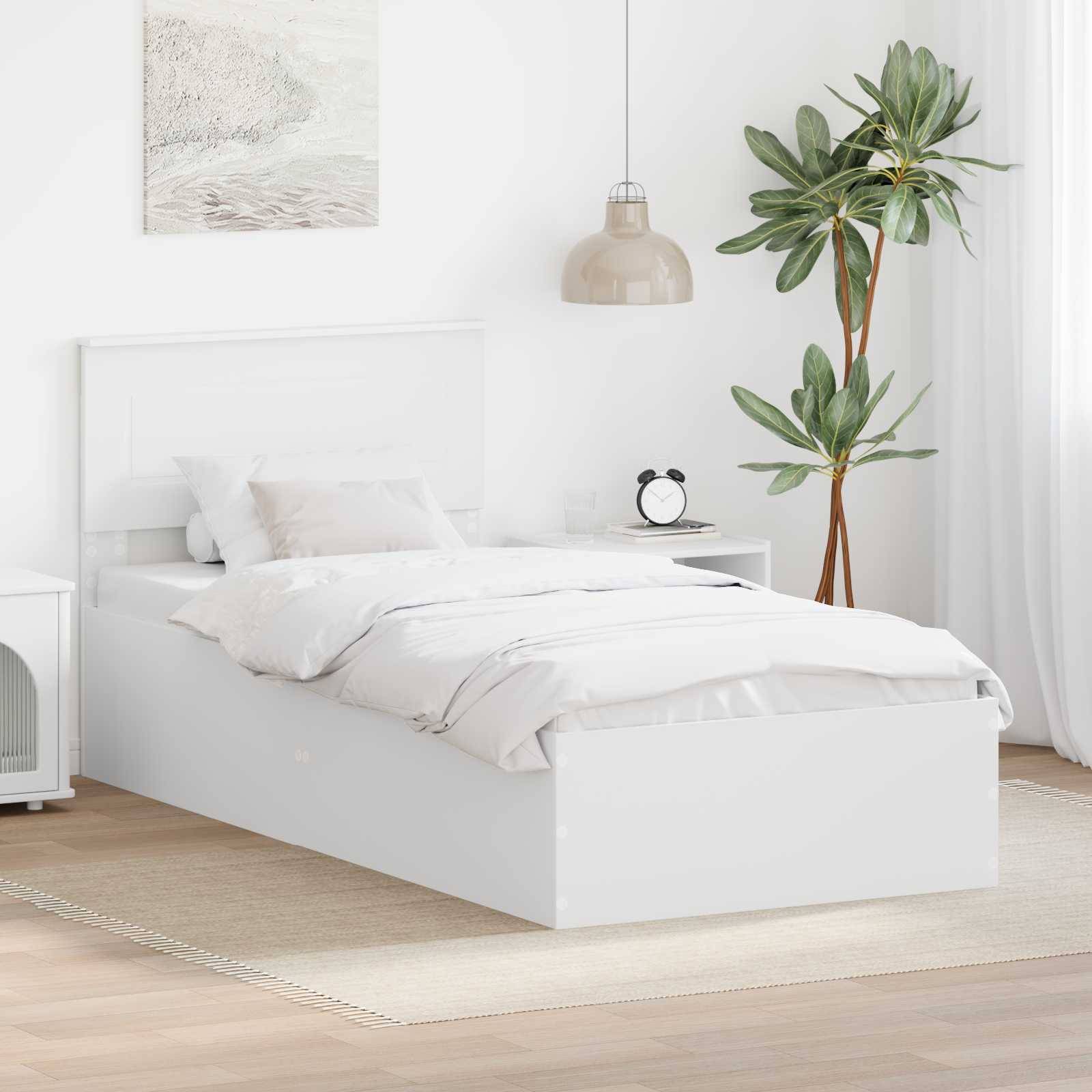 Ein minimalistisches Schlafzimmer mit einem weißen Bett, einem Nachttisch, einer Pendelleuchte, einer Topfpflanze und gerahmter Wandkunst. Neutrale Töne schaffen eine ruhige Atmosphäre.