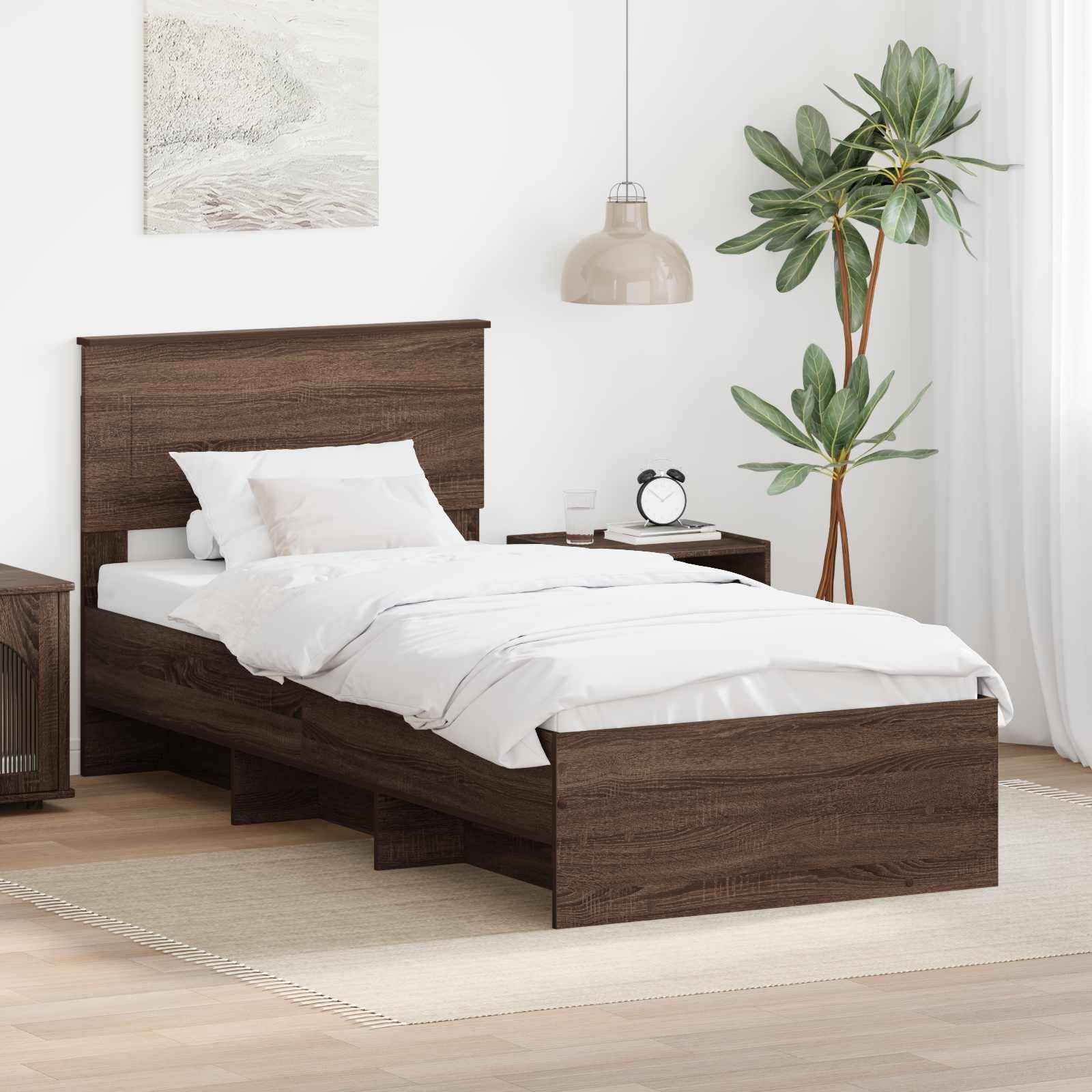 Ein ordentlich gemachtes Bett mit weißer Bettwäsche in einem modernen Schlafzimmer mit einem dunklen Holzrahmen. In der Nähe befinden sich ein Nachttisch, eine Pflanze und ein Teppich.
