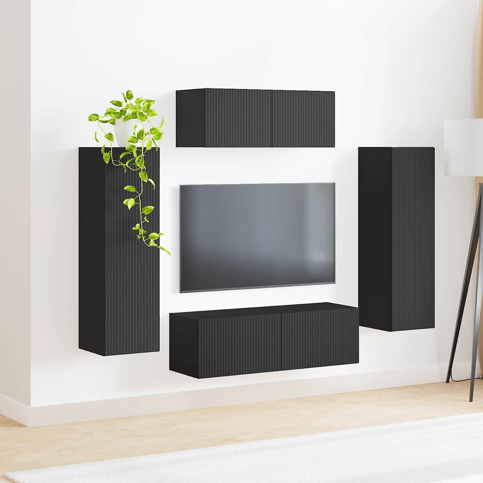 Ein moderner Wohnraum zeigt einen an der Wand montierten schwarzen Unterhaltungsbereich mit Schränken und einem Flachbildfernseher an einer hellgefärbten Wand.