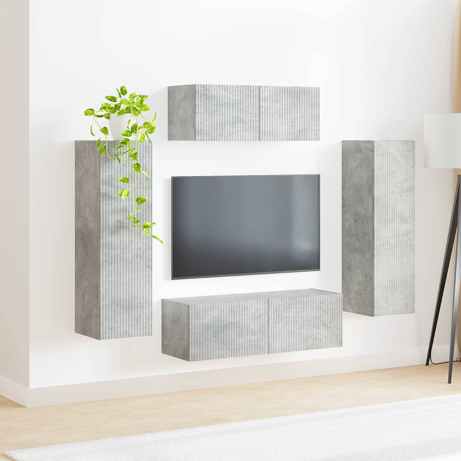 An der Wand montiertes graues Medienmöbel mit einem Flatscreen-Fernseher, ausgestattet mit vertikalen und horizontalen Schränken und einer kleinen Zimmerpflanze.