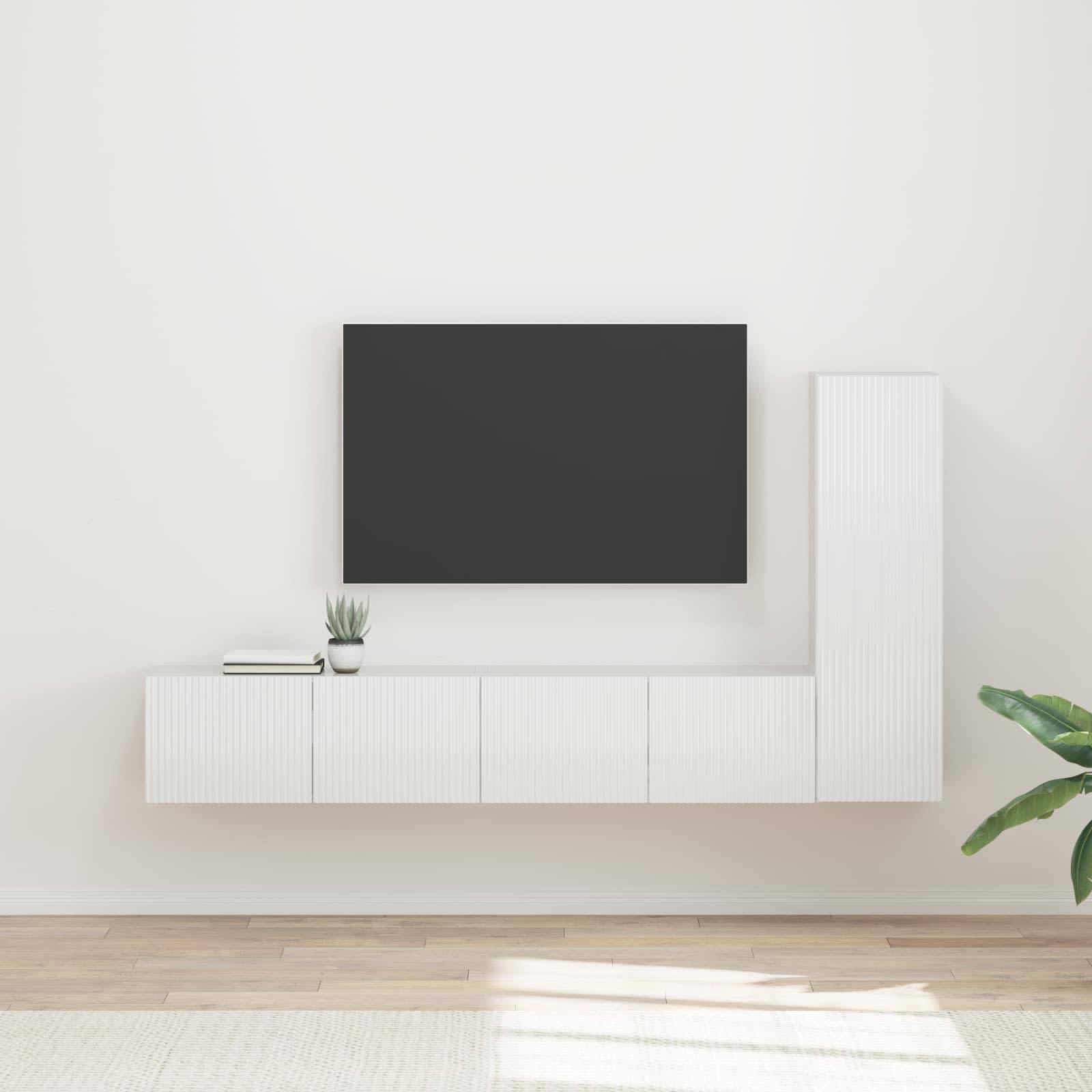 Ein minimalistisches Wohnzimmer mit einer an der Wand montierten TV, schlanken weißen Schränken darunter und einer Topfpflanze auf einem hellen Holzboden.