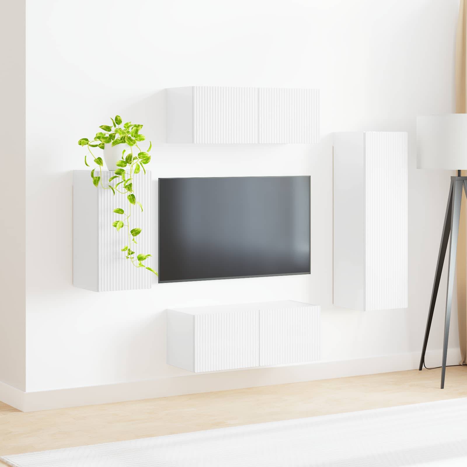 Ein moderner Wohnbereich zeigt einen an der Wand montierten Fernseher, umgeben von weißen, minimalistischen Schränken, wobei eine Topfpflanze einen Hauch von Grün hinzufügt.
