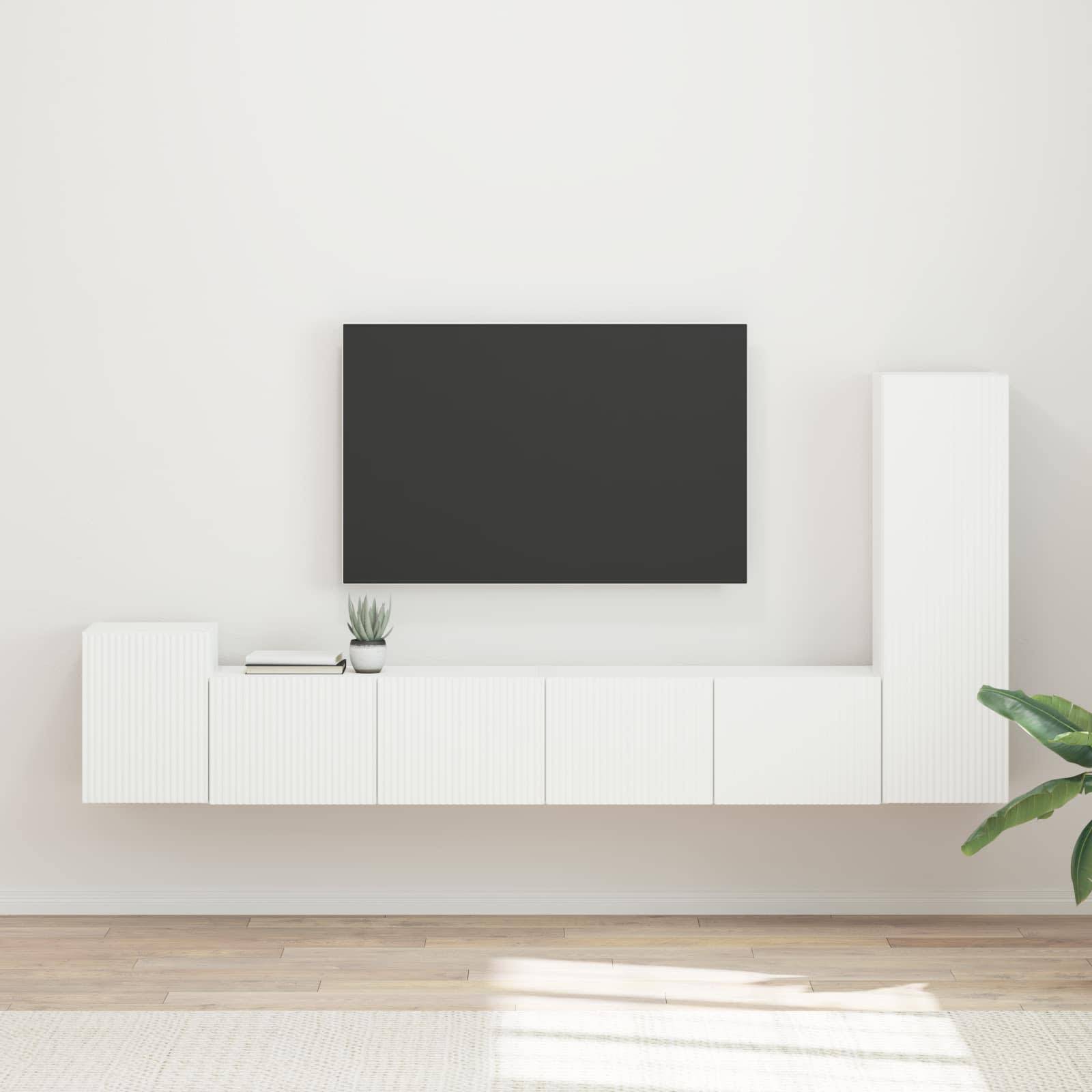 Ein minimalistisches Wohnzimmer mit einer wandmontierten Flachbild-TV, weißen modernen Schränken und einer großen grünen Pflanze auf der rechten Seite.