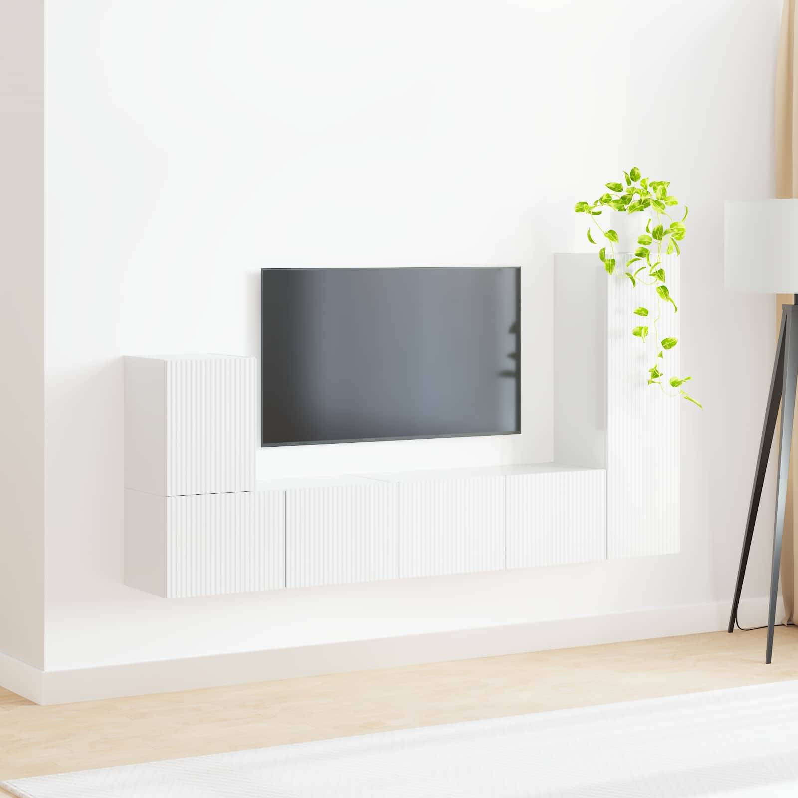 Ein moderner minimalistischer Wohnraum mit einem Flachbild-Fernseher an der Wand, weißen Schränken darunter und einer grünen Pflanze, die einen Kontrast bildet.