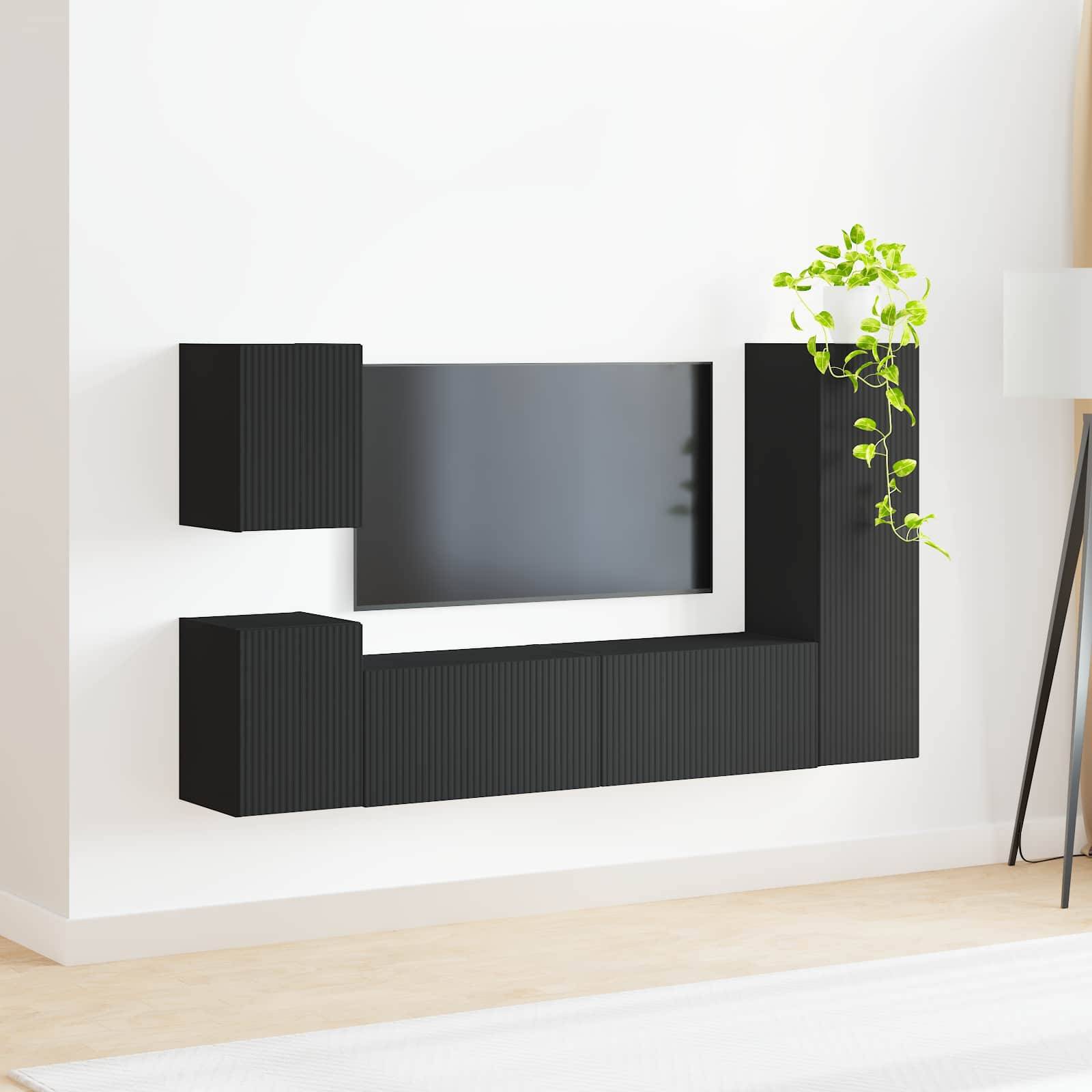 Ein minimalistisches, an der Wand montiertes schwarzes TV-Sideboard mit Regalelement und einer kleinen Topfpflanze obenauf, vor einer weißen Wand.