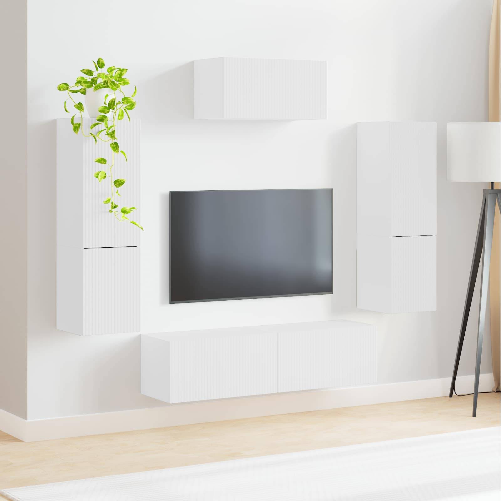Ein minimalistisches Wohnzimmer zeigt einen Flachbildschirm-Fernseher, der an einer Wand mit schlanken weißen Regalen zentriert ist. Eine Topfpflanze verleiht einen Hauch von Grün.