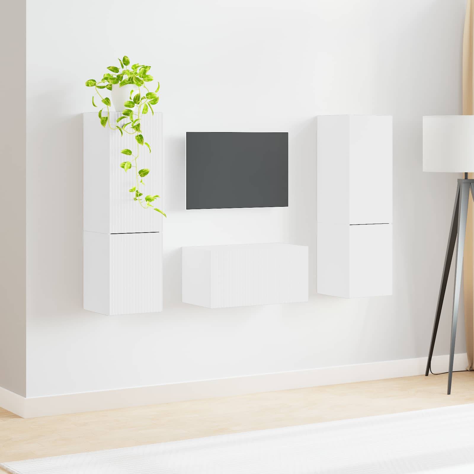 Ein minimalistisches Wohnzimmer mit weißen wandmontierten Schränken und einem kleinen Fernseher. Eine grüne Pflanze setzt einen Farbakzent. Der helle Holzboden verstärkt die luftige Atmosphäre.