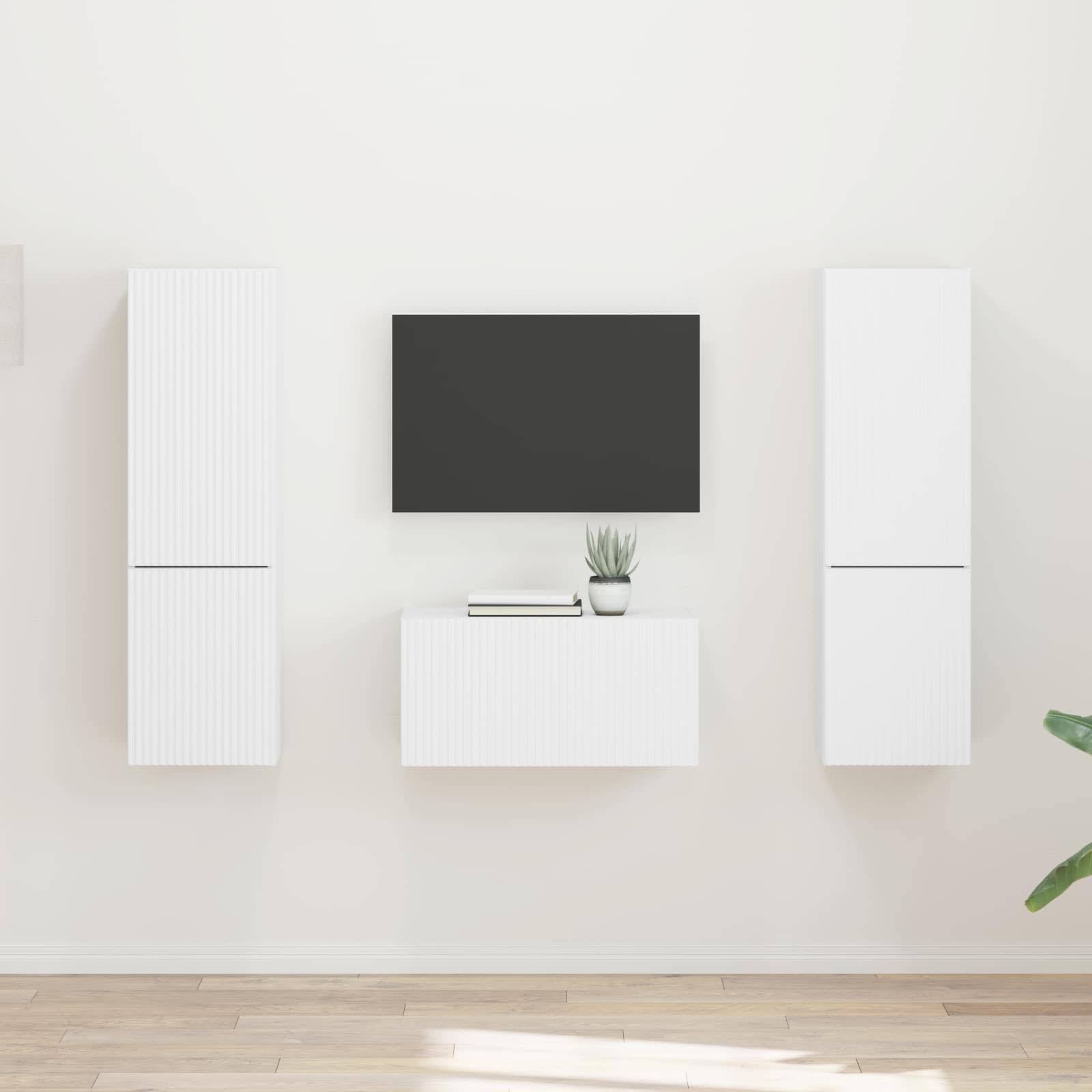 Ein minimalistisches Wohnzimmer mit einem ausgeschalteten Fernseher an einer hellen Wand, weißen Schränken und einer kleinen Pflanze auf einem Regal. Das Design ist schlicht und modern.