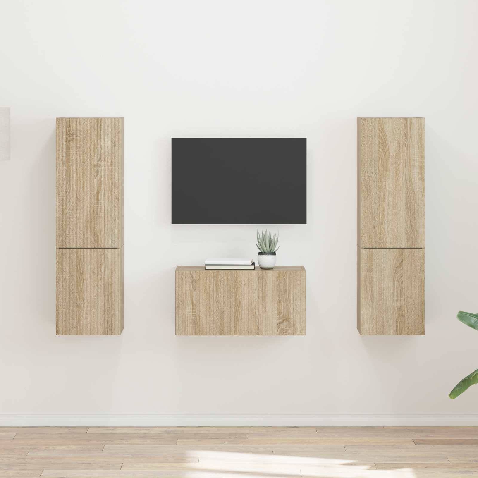 Minimalistisches Wohnzimmer mit hellen Holzwandschränken und einem schwarzen Fernsehbildschirm in der Mitte, vor einer hellgrauen Wand.
