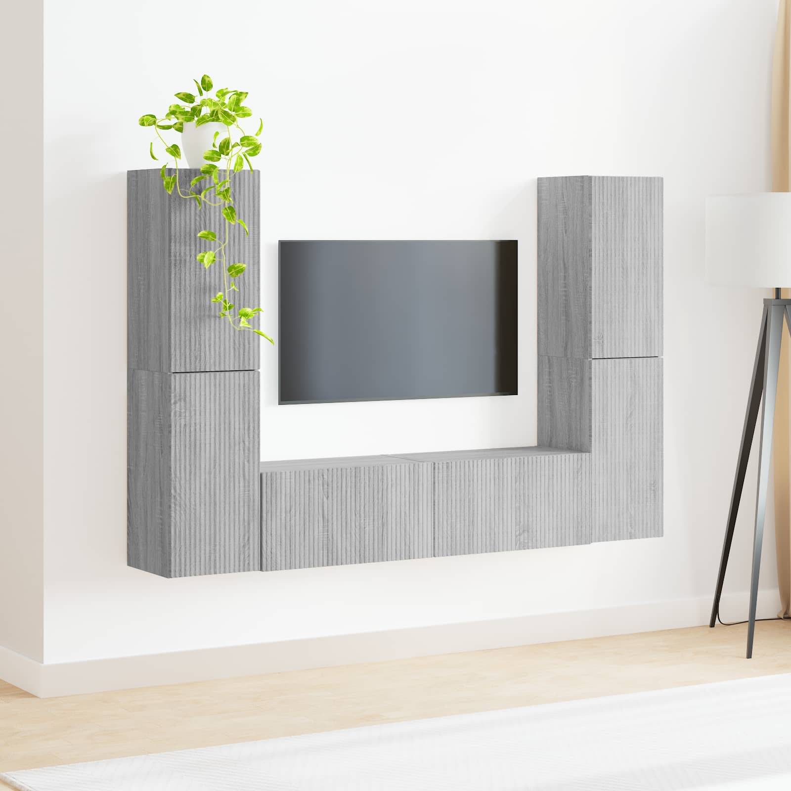 Ein minimalistischer Raum zeigt ein graues, an der Wand montiertes Regal in U-Form, das einen Flachbildfernseher umgibt, mit einer kleinen Pflanze oben drauf.
