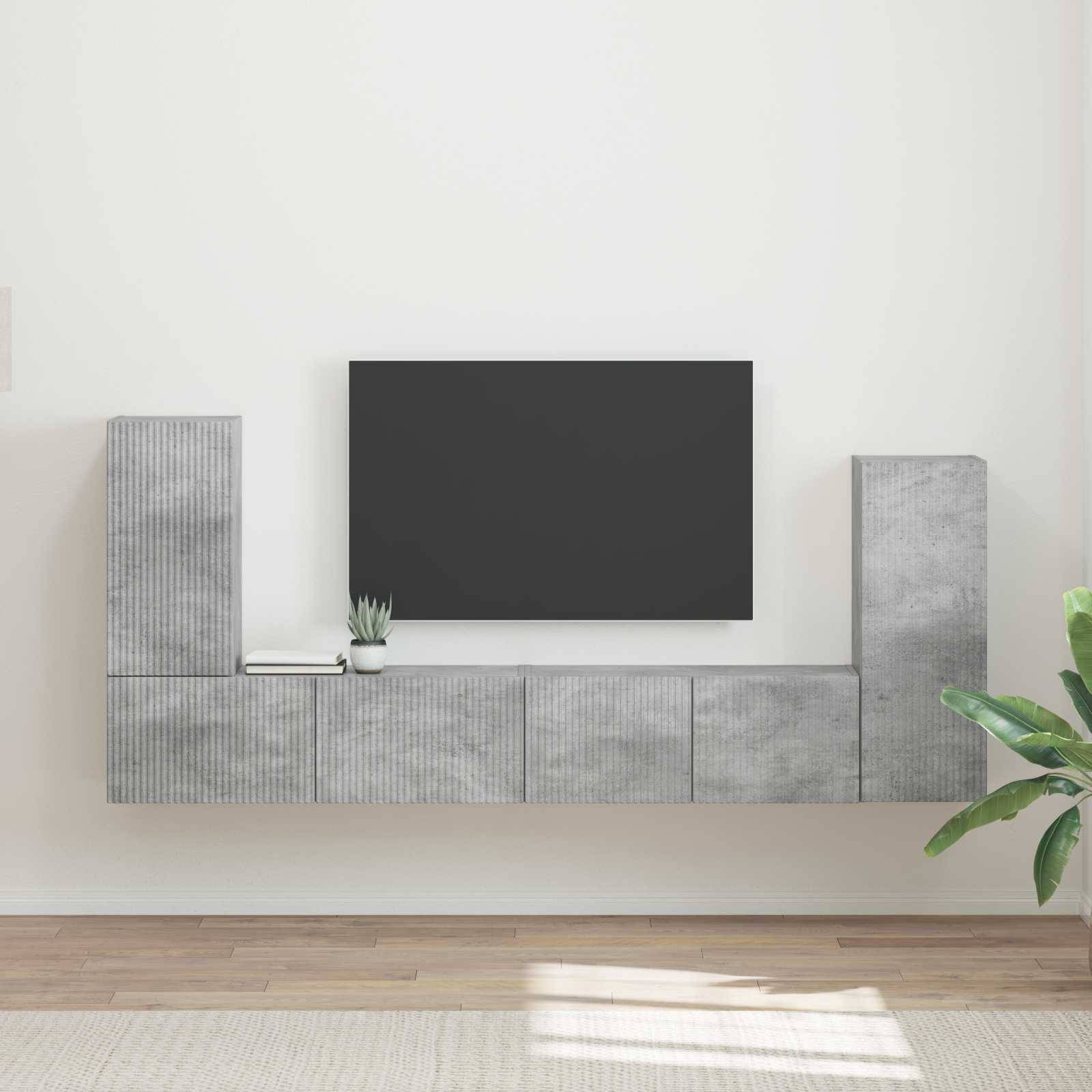 Ein moderner Wohnraum mit minimalistischen grauen Schränken und einem großen schwarzen Fernseher, der an einer beigen Wand montiert ist. Eine kleine Pflanze und ein Teppich setzen dezente Akzente.