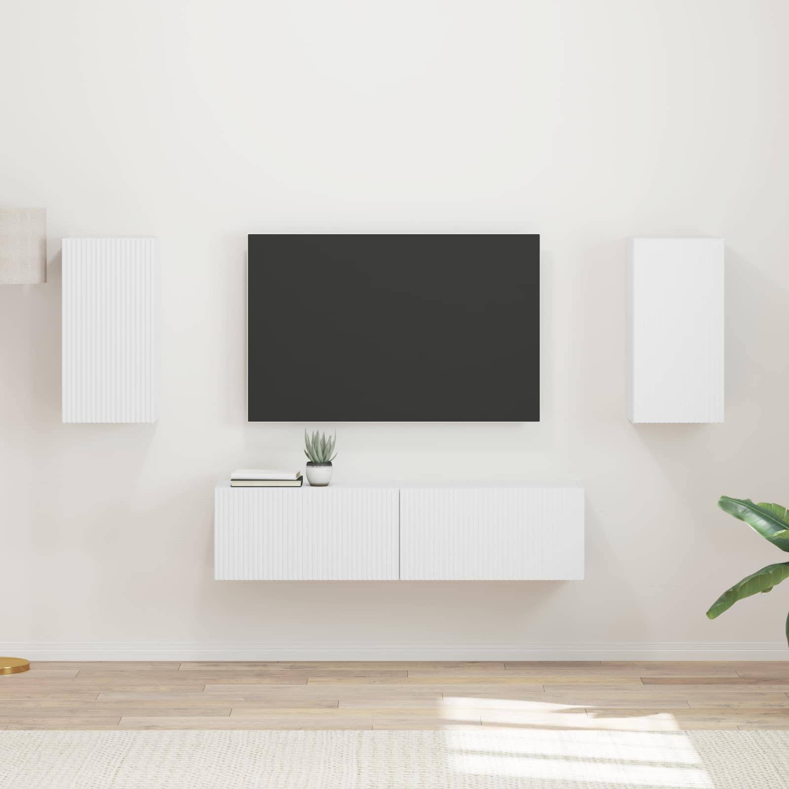 Ein minimalistisches Wohnzimmer zeigt einen an der Wand montierten Fernseher, der von weißen Schränken und einer kleinen Pflanze flankiert wird, vor einer hellen Wand und hellem Boden.
