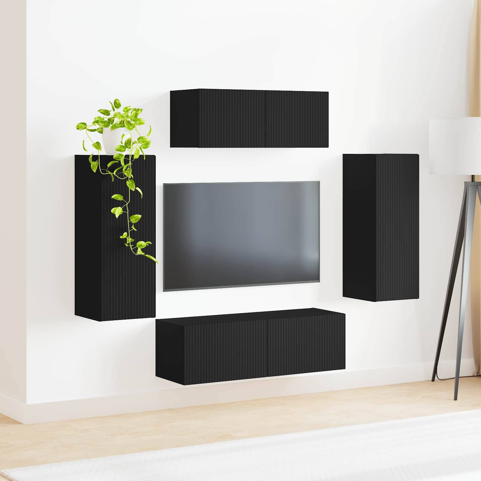 Moderner Wohnraum mit schwarzen wandmontierten Schränken um einen Flachbildfernseher herum. Eine grüne Pflanze setzt links auf dem Schrank einen kontrastierenden Akzent.