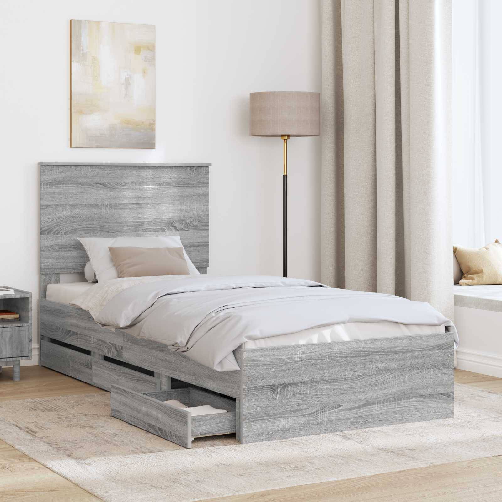 Ein modernes Schlafzimmer mit einem Bett aus grauem Holz, das Stauraum unter dem Bett bietet, beigefarbener Bettwäsche, einer Stehlampe und einer Fensterbank mit leichten Vorhängen.