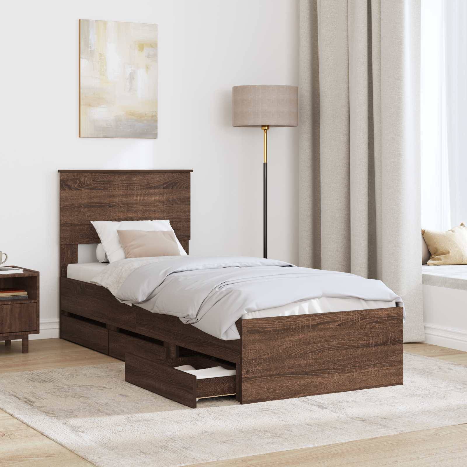 Ein graues Doppelbett mit minimalistischem Design, mit Kopfteil und drei ausziehbaren Schubladen darunter. Es ist mit hellblauer Bettwäsche bezogen.