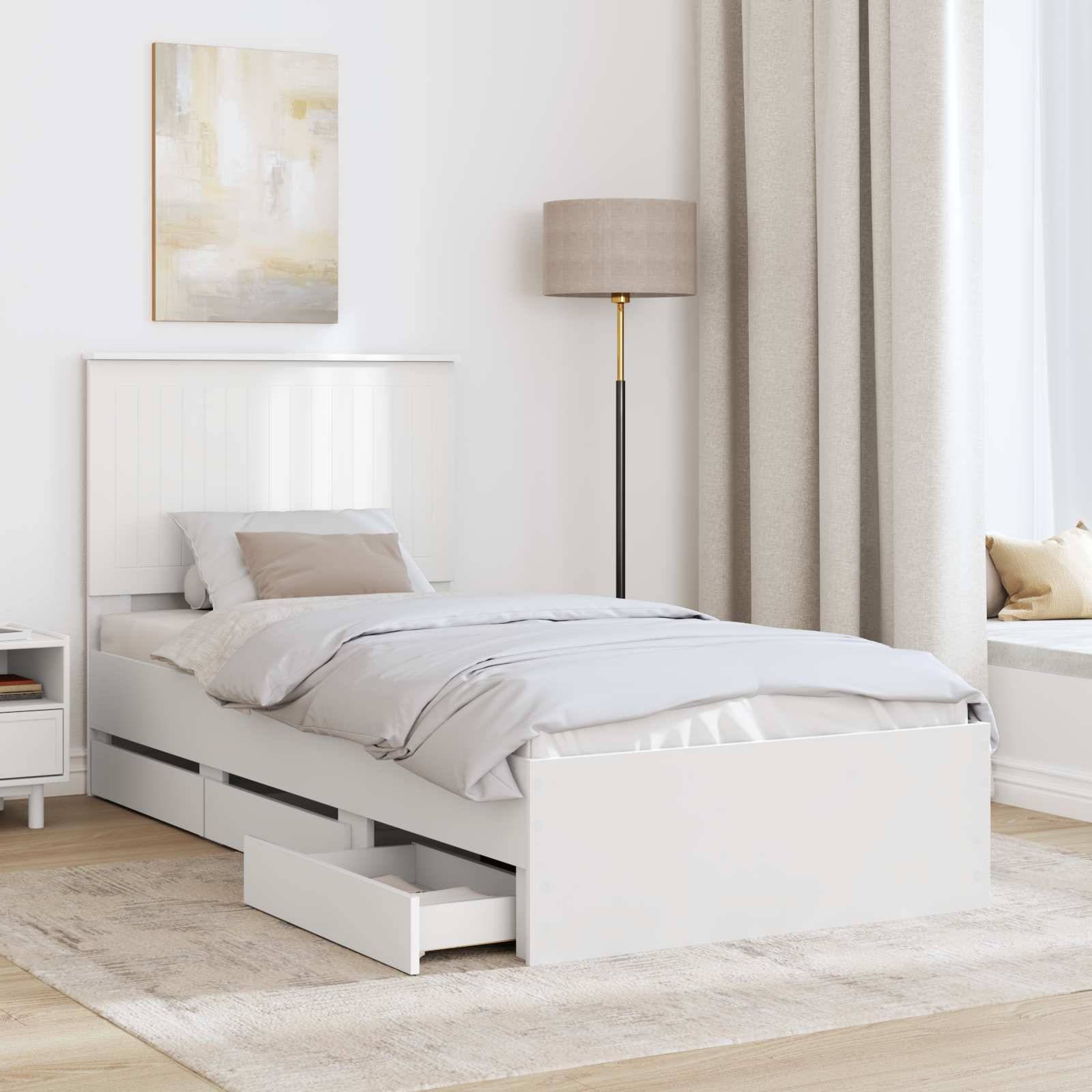 Ein minimalistisches Schlafzimmer mit einem weißen Einzelbett mit ausziehbarer Schublade, beigefarbener Bettwäsche, einer Lampe, Kunstwerken an der Wand und einer Fensterbank zum Sitzen.